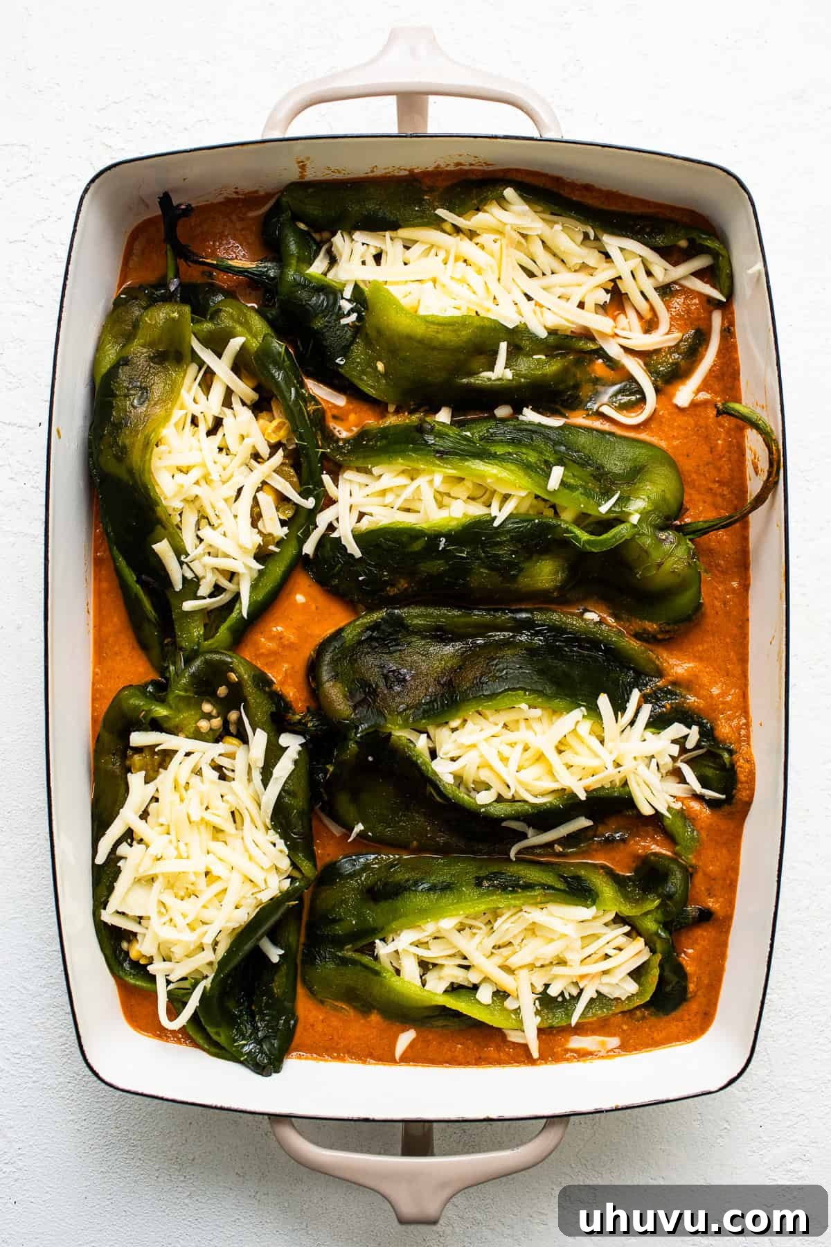 Easy Baked Chile Rellenos 6 Baked chile relleno in a baking dish before being baked, covered in ranchero sauce.