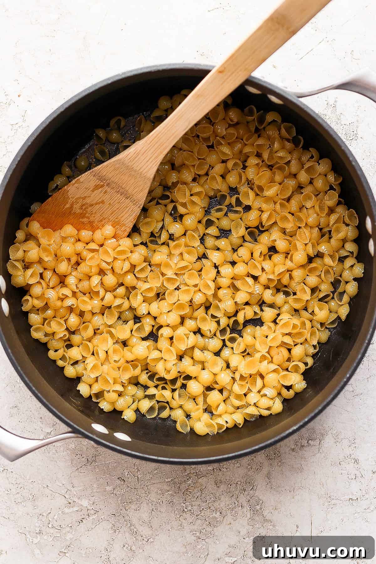 Little Shell Pasta Soup 5 Small shell pasta for Sopa de Conchas being gently toasted in olive oil within a pot, turning golden brown.