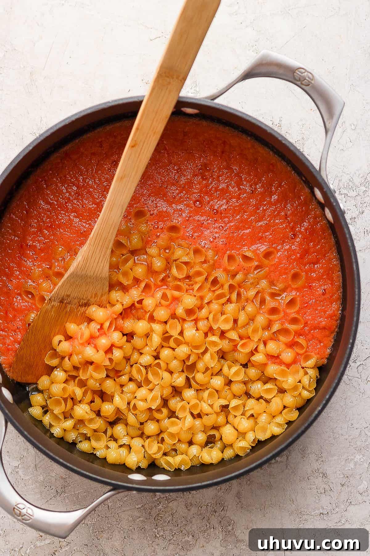 Little Shell Pasta Soup 6 Vibrant blended tomato broth being stirred into a pot of golden-brown toasted shell pasta, beginning the creation of Sopa de Conchas.