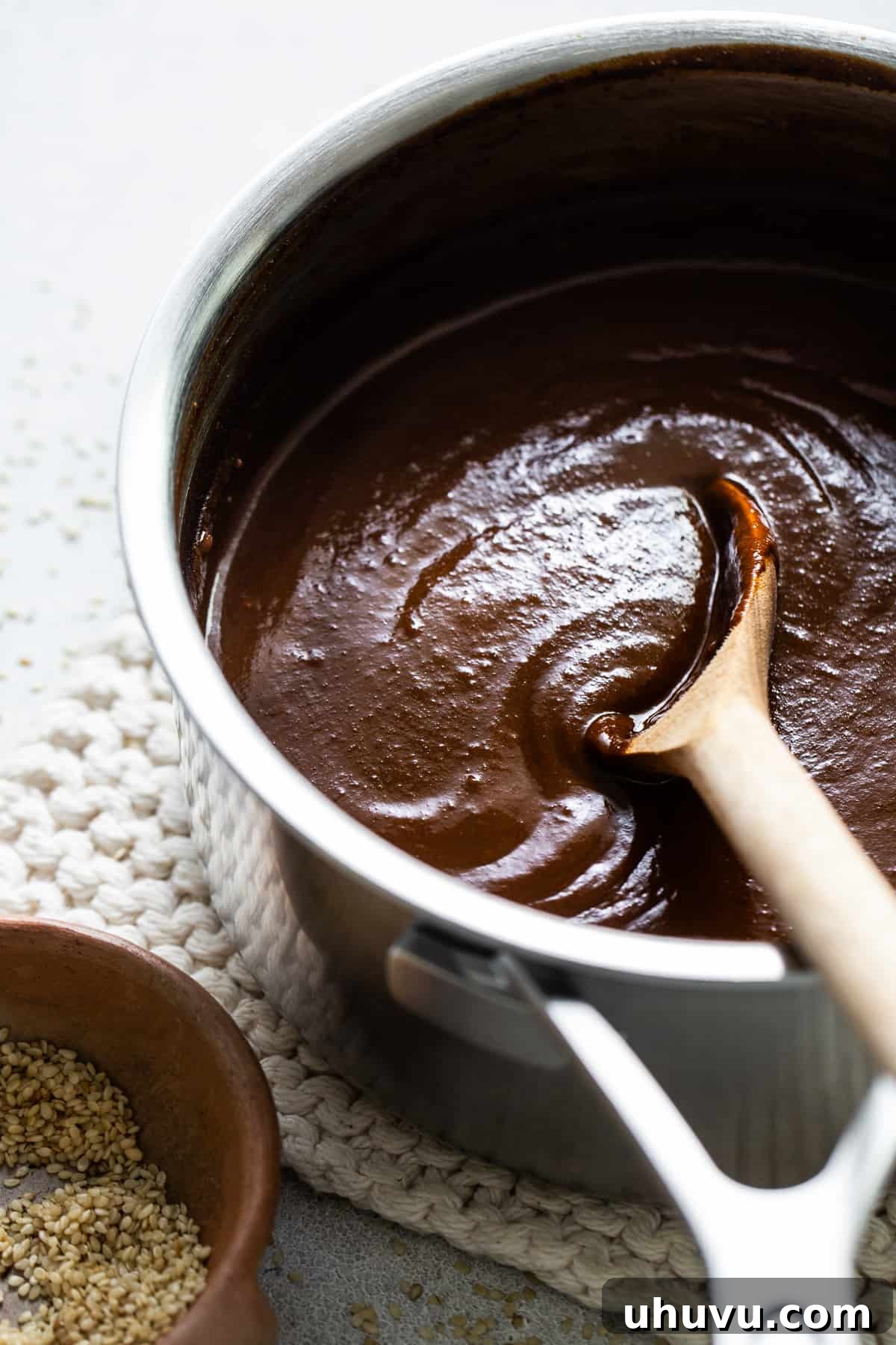 Mexican Mole Bliss 4 A rich, dark mole sauce simmering gently in a saucepan, being stirred with a wooden spoon, ready to coat the enmoladas.