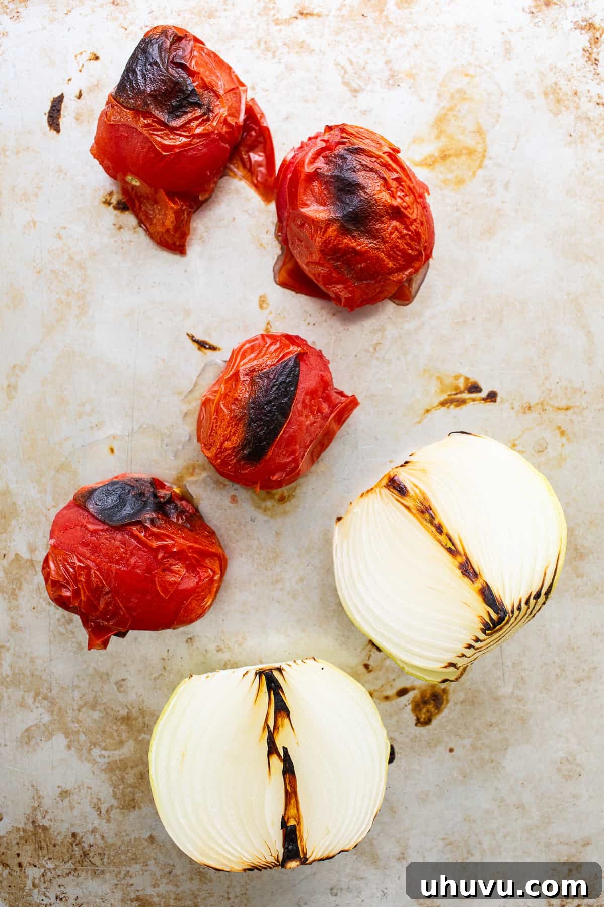 Smoky Chipotle Chicken Tinga 5 Roasted Roma tomatoes and a white onion, perfectly charred on a baking sheet, ready for blending into the flavorful tinga sauce.