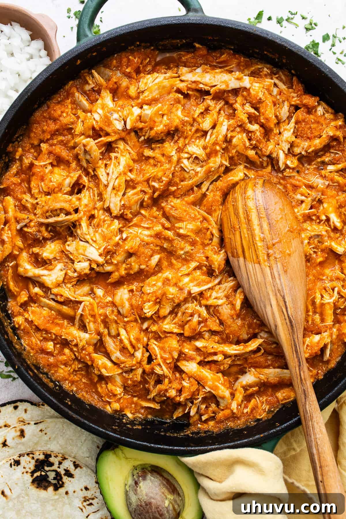Smoky Chipotle Chicken Tinga 7 A large pot filled with saucy shredded chicken tinga, being expertly stirred with a wooden spoon, showcasing its rich, vibrant color and perfect consistency.