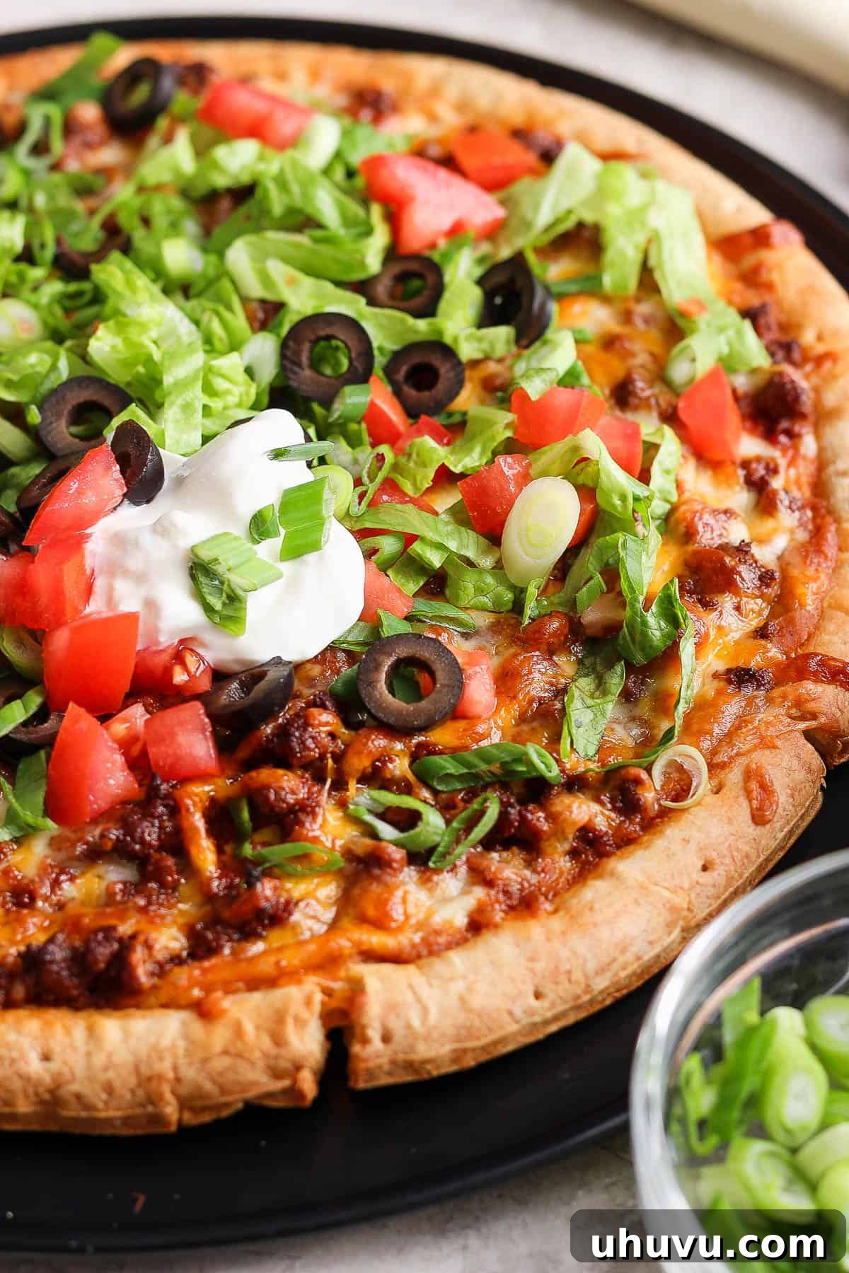 Zesty Mexican Pizza 11 Taco pizza topped with shredded lettuce, sour cream, diced tomatoes, and olives.