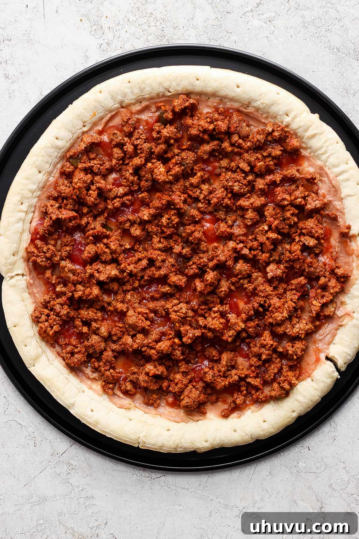 Zesty Mexican Pizza 7 Salsa spread over refried beans on pizza crust.