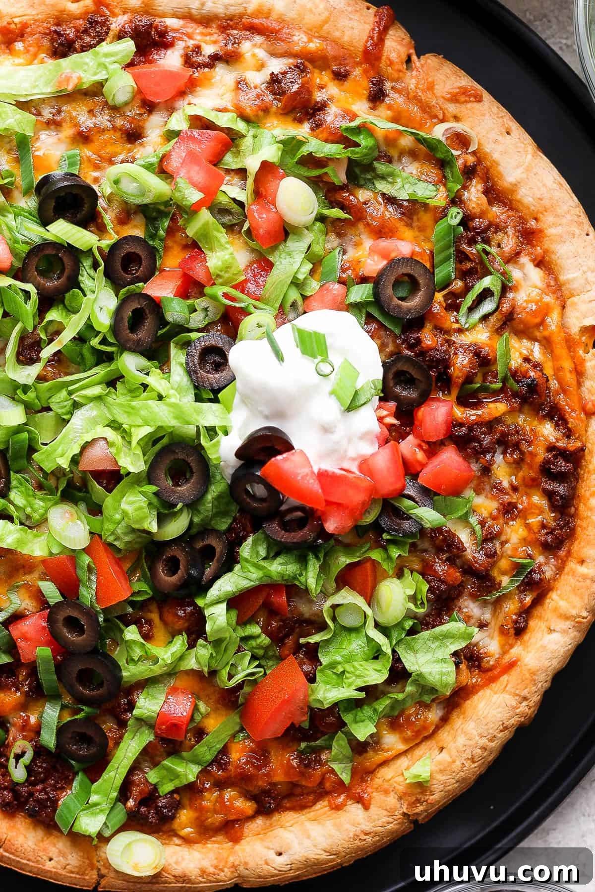 Zesty Mexican Pizza 10 An easy and mouthwatering taco pizza, adorned with a swirl of sour cream, a bed of shredded lettuce, vibrant diced tomatoes, and other classic taco toppings.