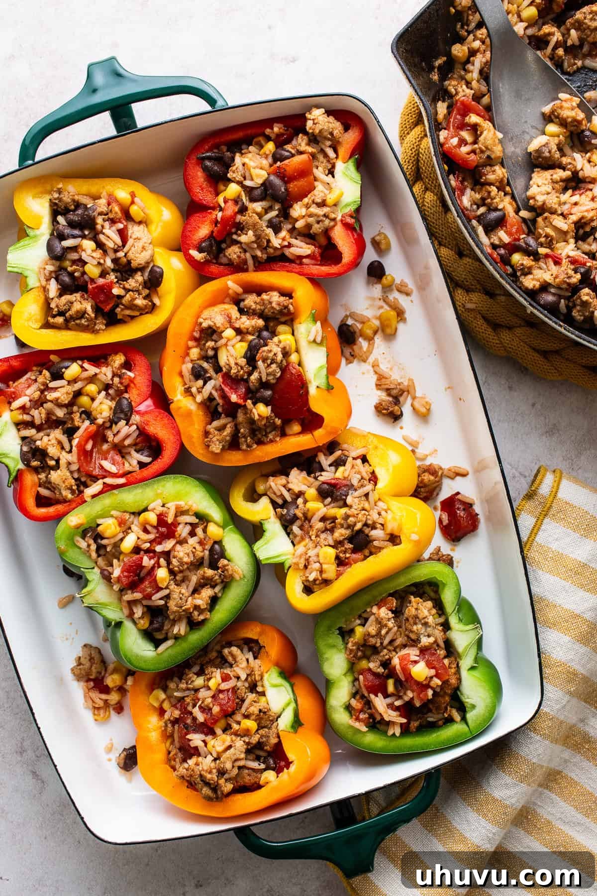 Fiesta Stuffed Peppers 6 Mexican stuffed peppers arranged in a baking dish, filled with the savory mixture and topped with cheese, awaiting baking.