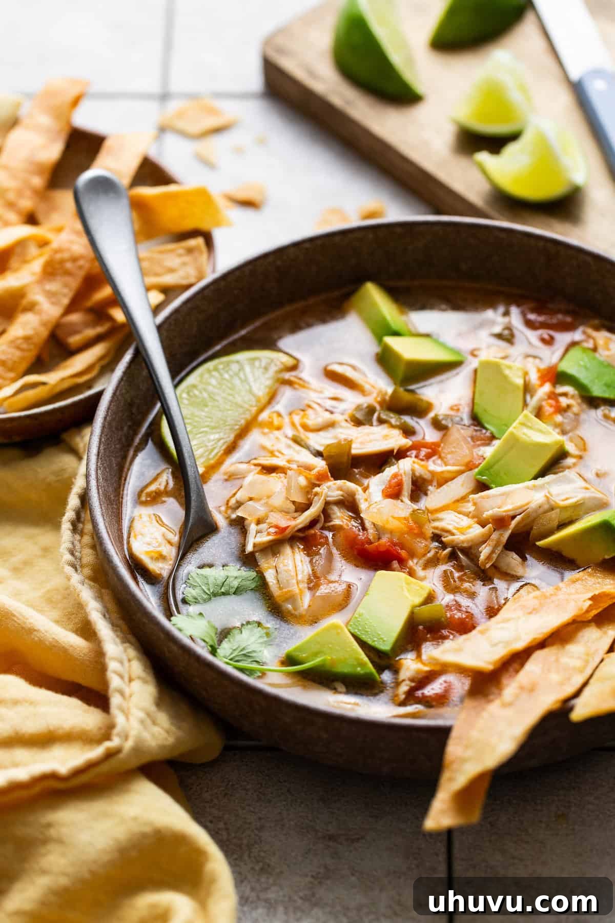 Authentic Yucatecan Lime Soup 8 Sopa de lima served into bowls with tortillas trips, limes,, diced avocados and cilantro.