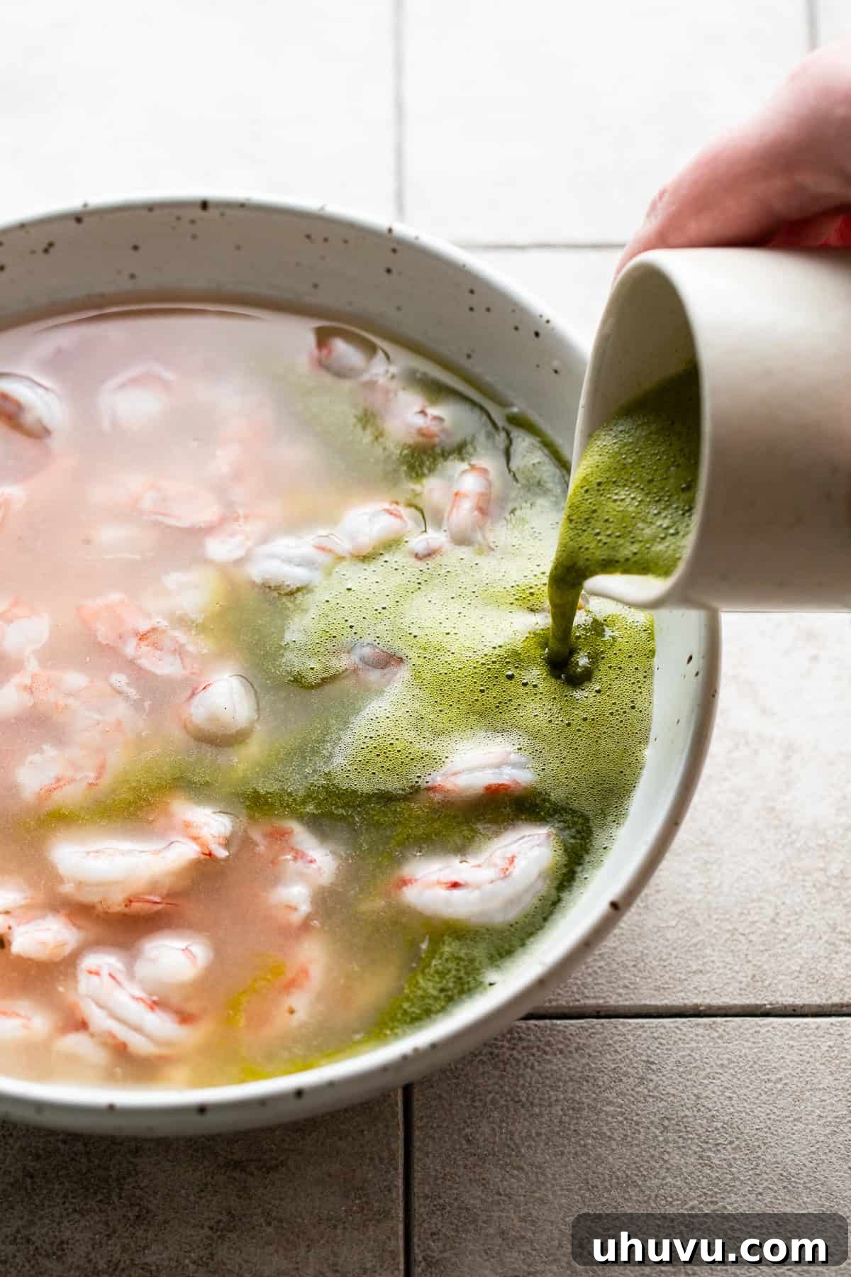 Chili Lime Shrimp 6 The blended cilantro, serrano, and lime juice mixture being poured into a bowl of shrimp aguachile.