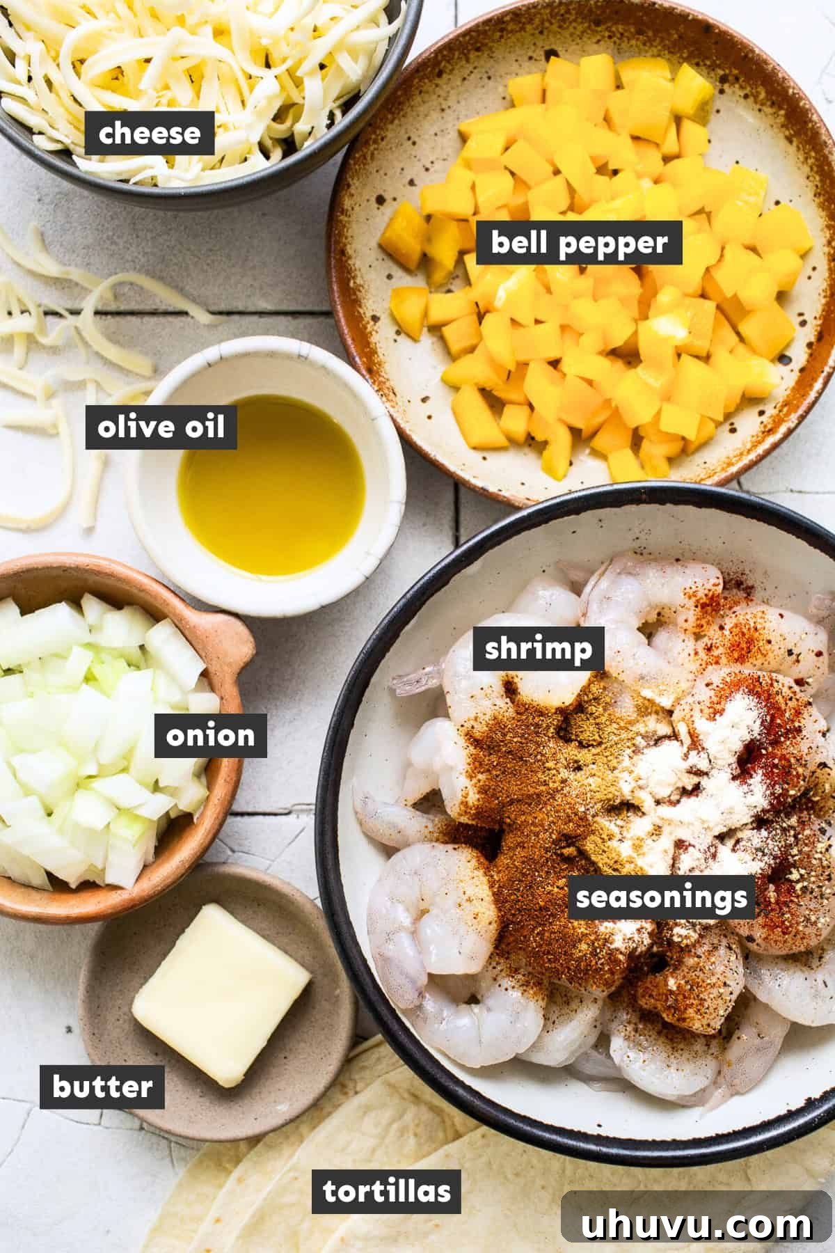 Zesty Shrimp Queso Melts 3 A selection of fresh ingredients for shrimp quesadillas laid out on a rustic wooden table: raw chopped shrimp, diced bell peppers and onions, a bowl of spices, flour tortillas, and a block of cheese.