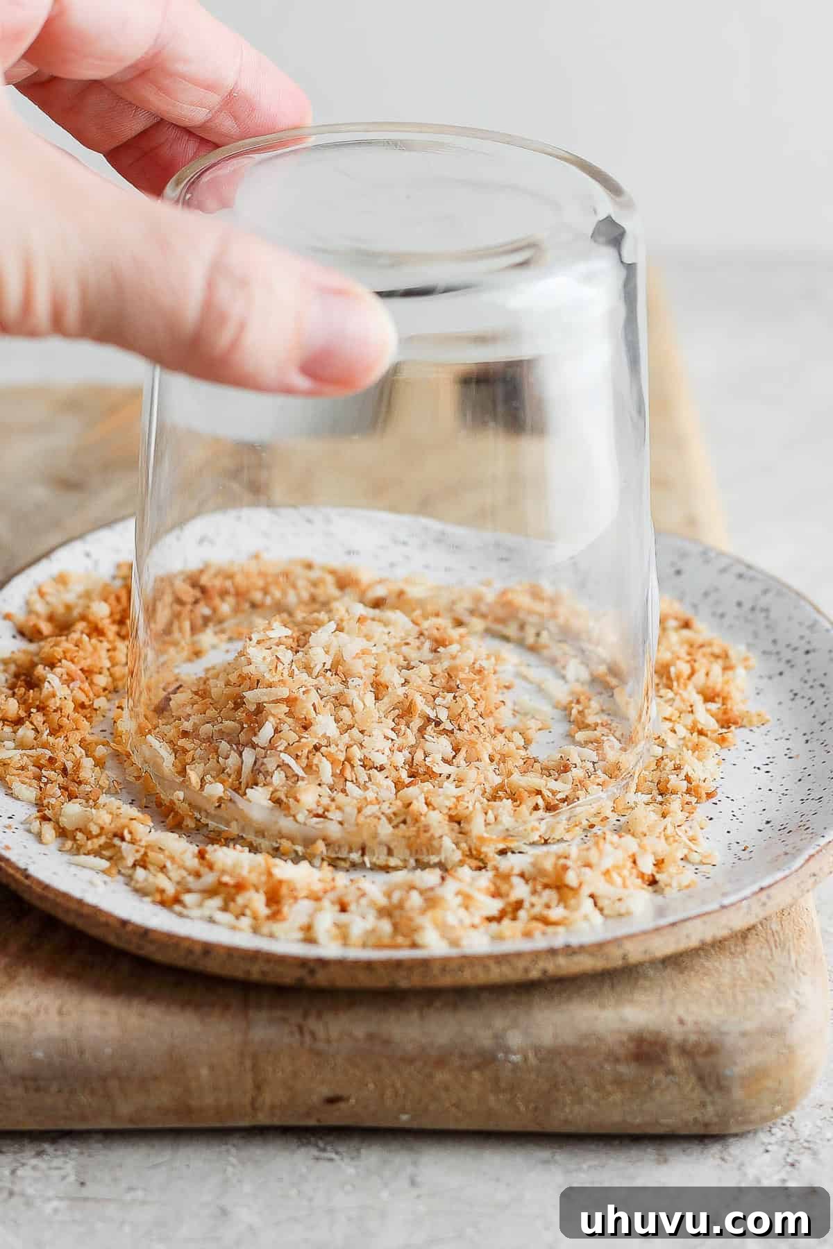 Tropical Coconut Margarita 6 A cocktail glass being rimmed with toasted coconut flakes