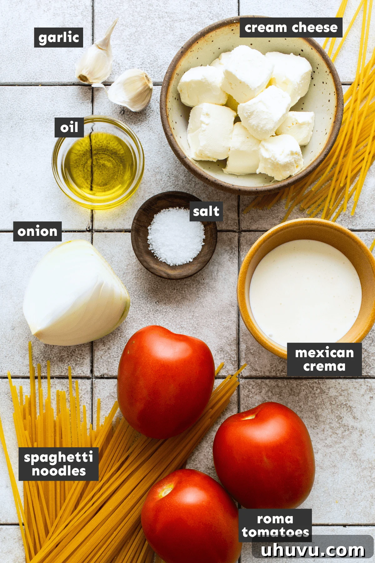Crimson Spaghetti 3 Fresh ingredients laid out on a wooden table, including Roma tomatoes, garlic, onion, Mexican crema, cream cheese, and a package of spaghetti, all ready for making Espagueti Rojo.