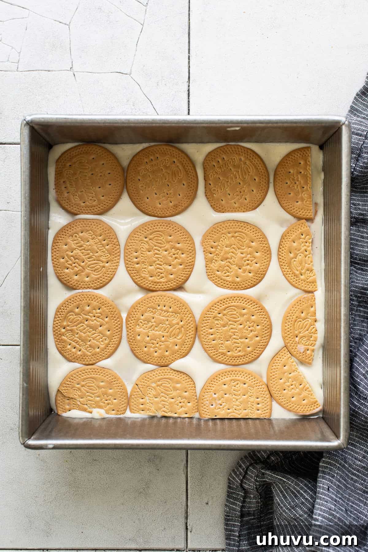 Assembled even layers of Marias cookies and key lime mixture in a baking sheet, ready for chilling.