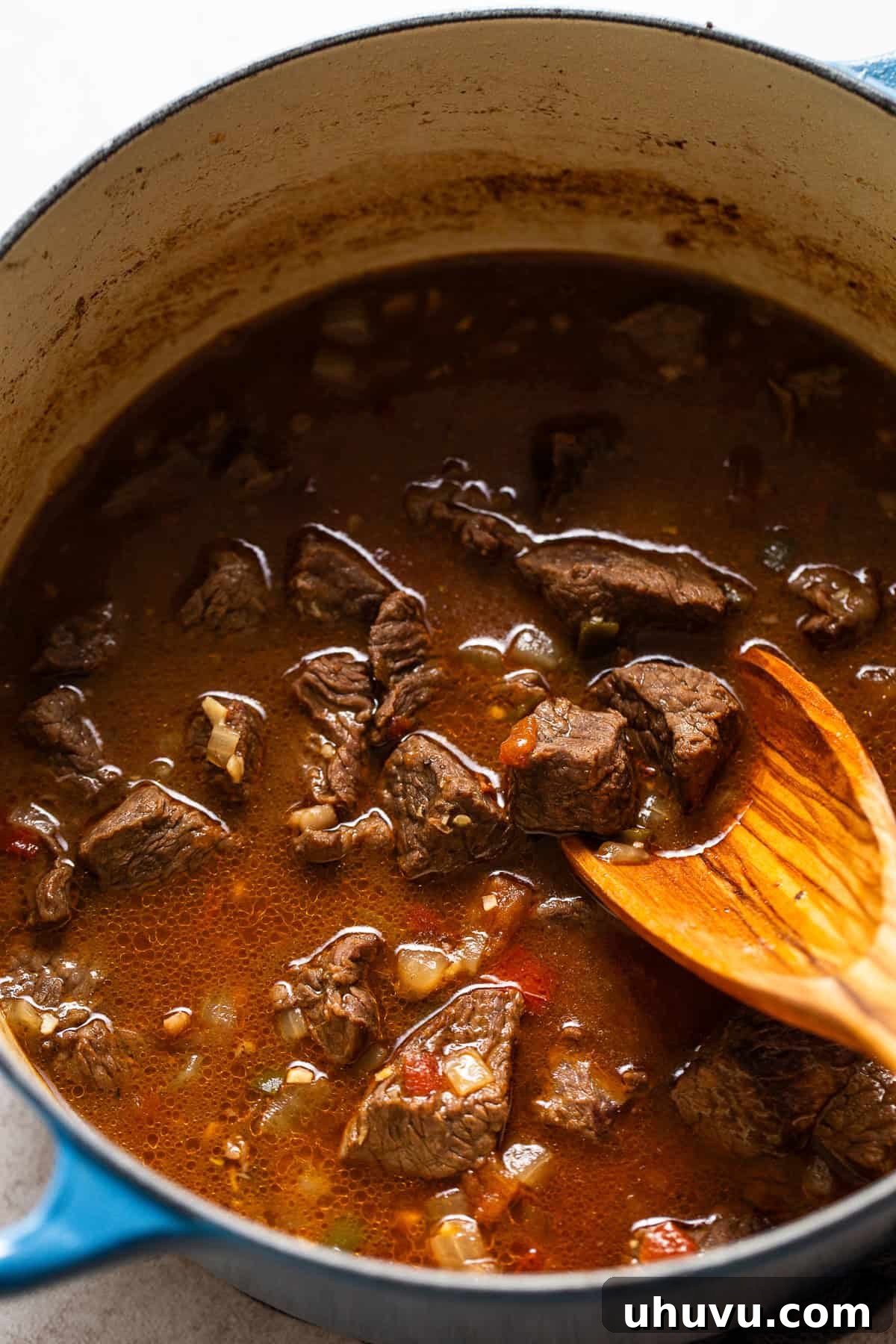 Slow-Simmered Beef Perfection 6 Diced Roma tomatoes added to the pot with the beef and aromatics, simmering to create a rich, thick, tomato-based gravy for the Carne Guisada.