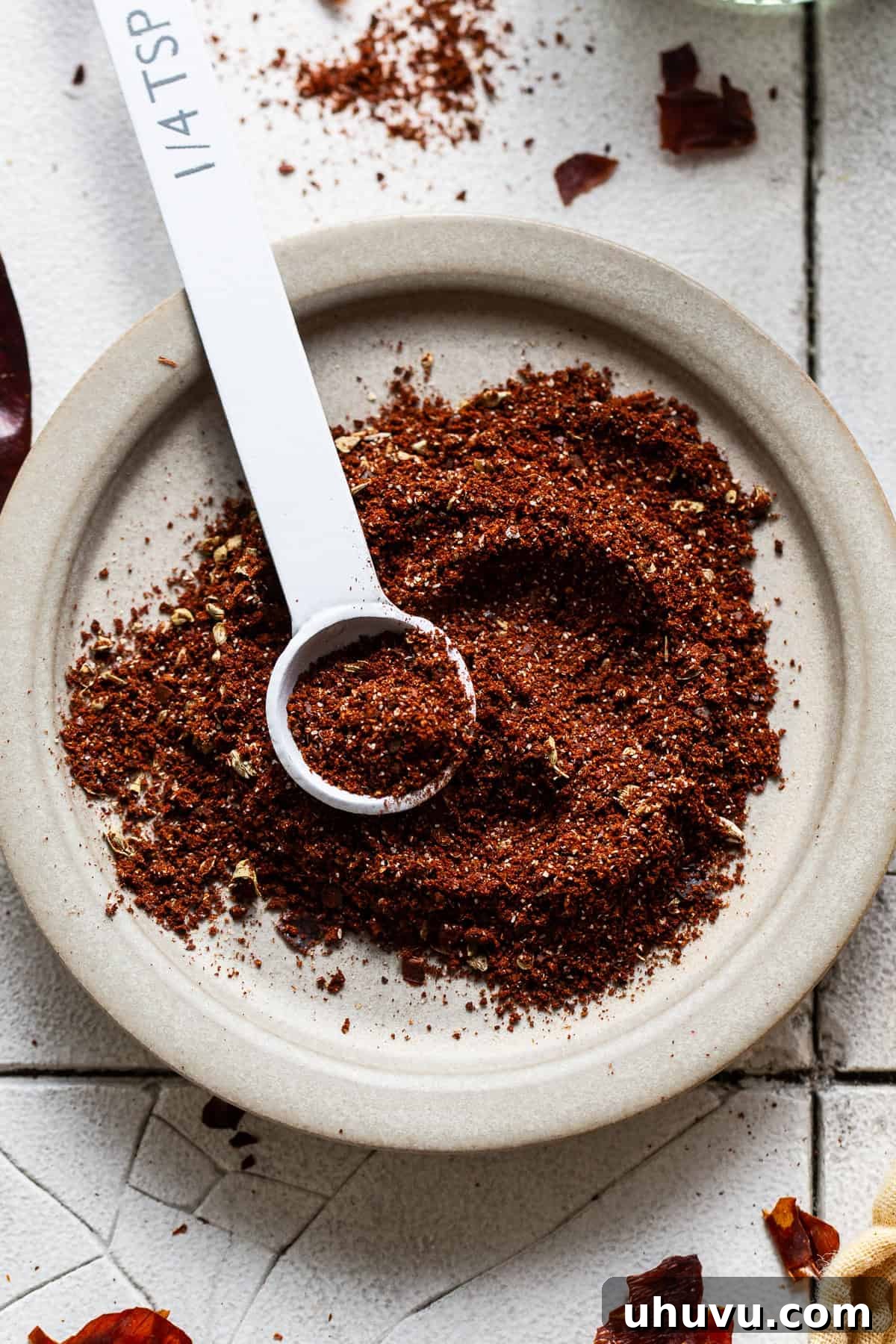Your Signature Chili Powder Blend 7 A small plate of homemade chili powder with a measuring spoon, prepared for use in various recipes.