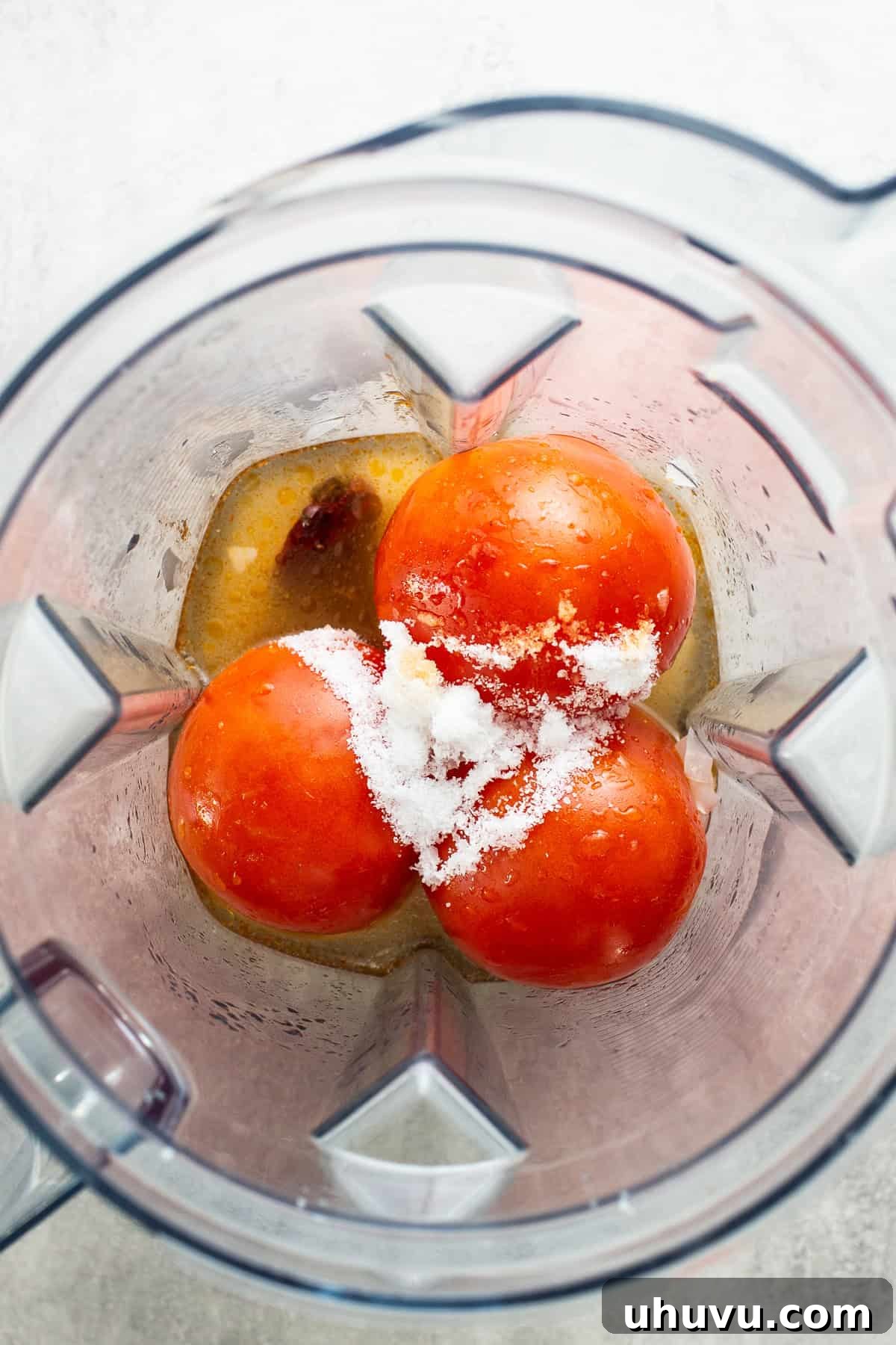Roma tomatoes, salt, and a portion of chicken broth being blended together in a blender to create the base for the Caldo Tlalpeño's flavorful tomato mixture.