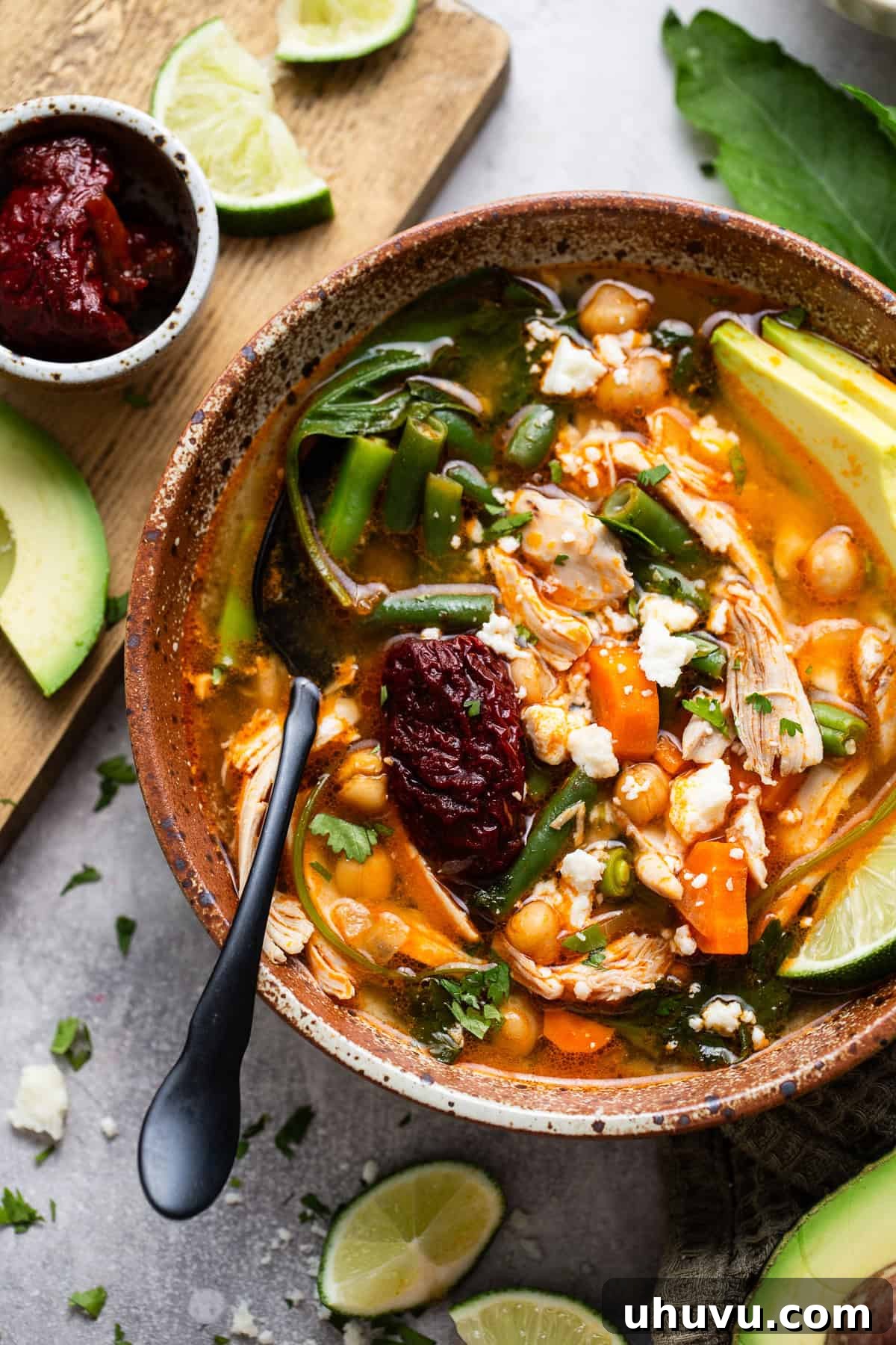 Caldo Tlalpeño garnished with a chipotle pepper in adobo sauce, queso fresco, and cilantro.