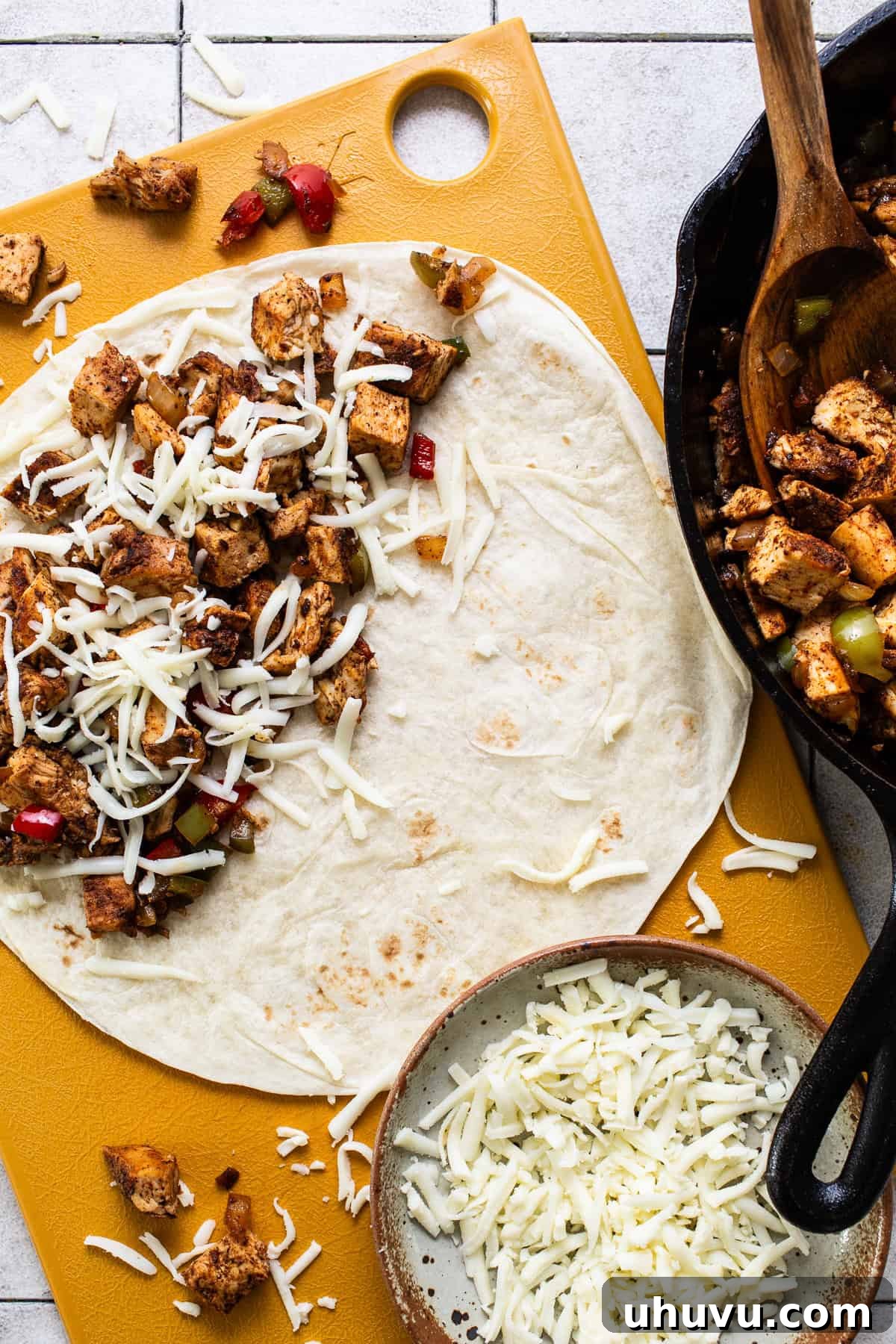 Zesty Chicken Fajita Quesadilla 6 A flour tortilla being generously filled with chicken fajita mixture and shredded cheese before folding.