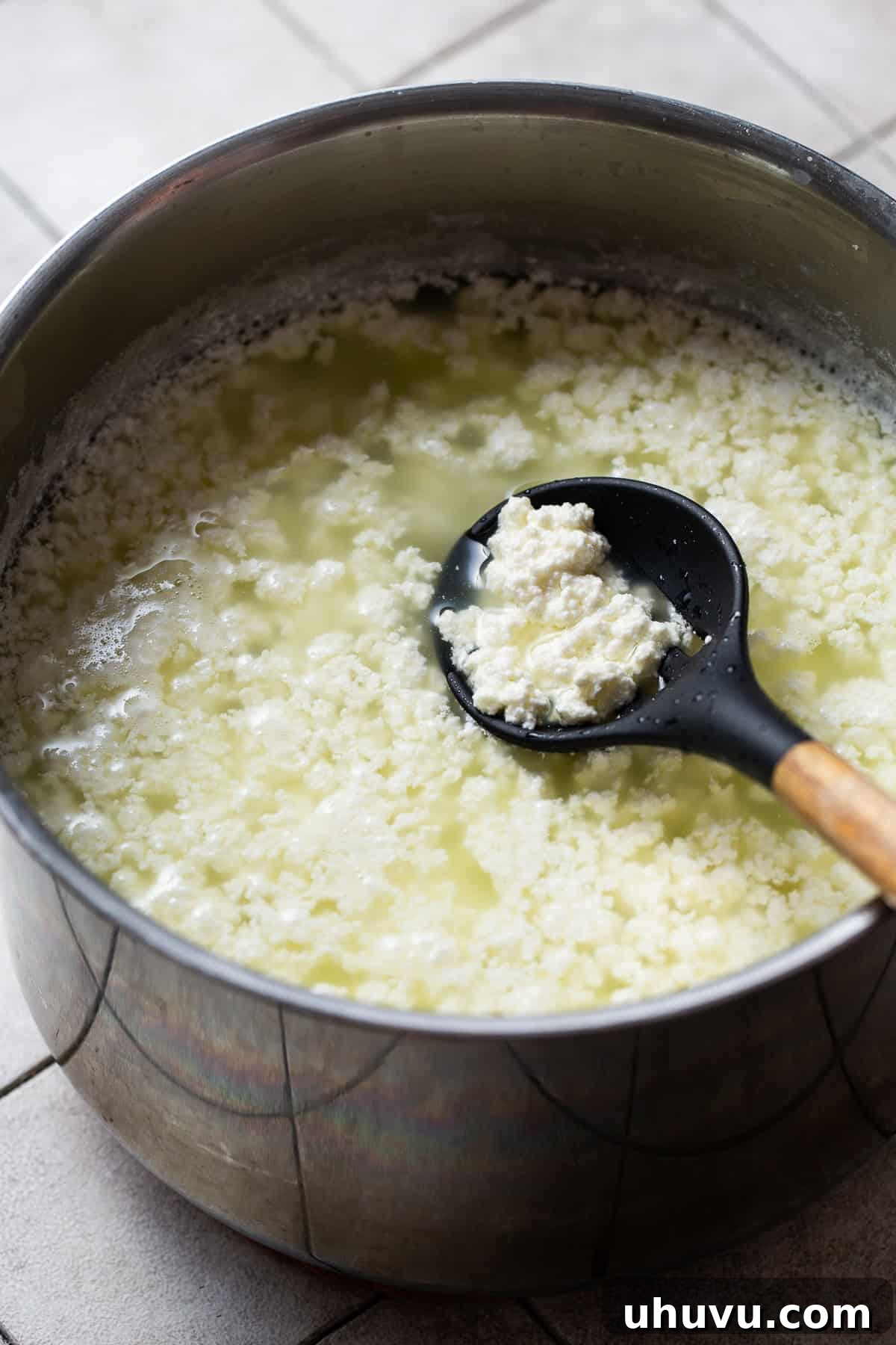 Make Your Own Queso Fresco 4 Milk and vinegar beginning to curdle in a large pot on the stove, showing the initial stages of queso fresco formation.