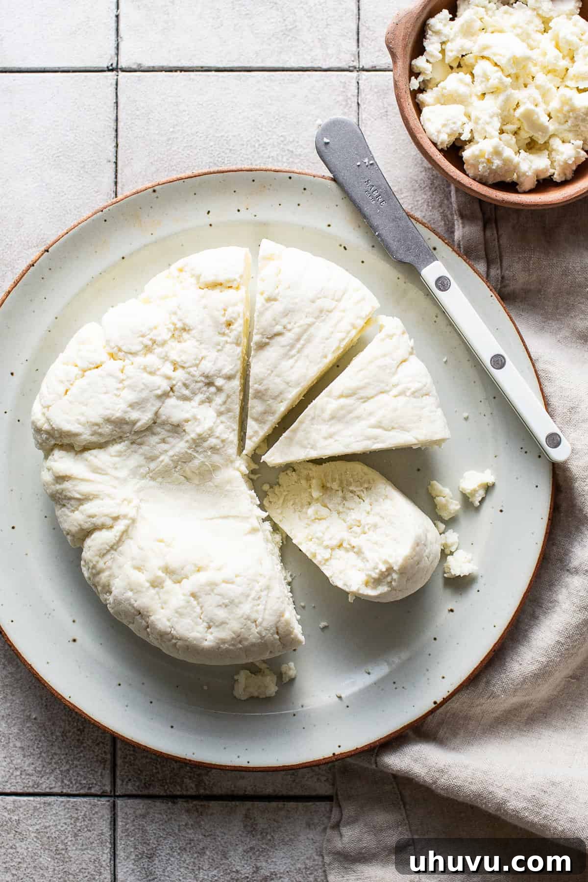Make Your Own Queso Fresco 8 A freshly made block of queso fresco, uncovered and placed on a plate, cut into neat wedges.