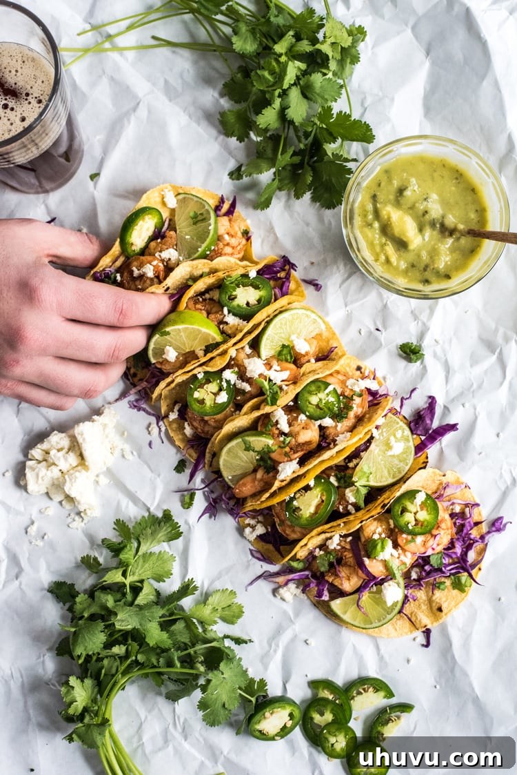 Arrangement of Honey Balsamic Beer Shrimp Tacos with various fresh toppings like red cabbage, cilantro, and lime.