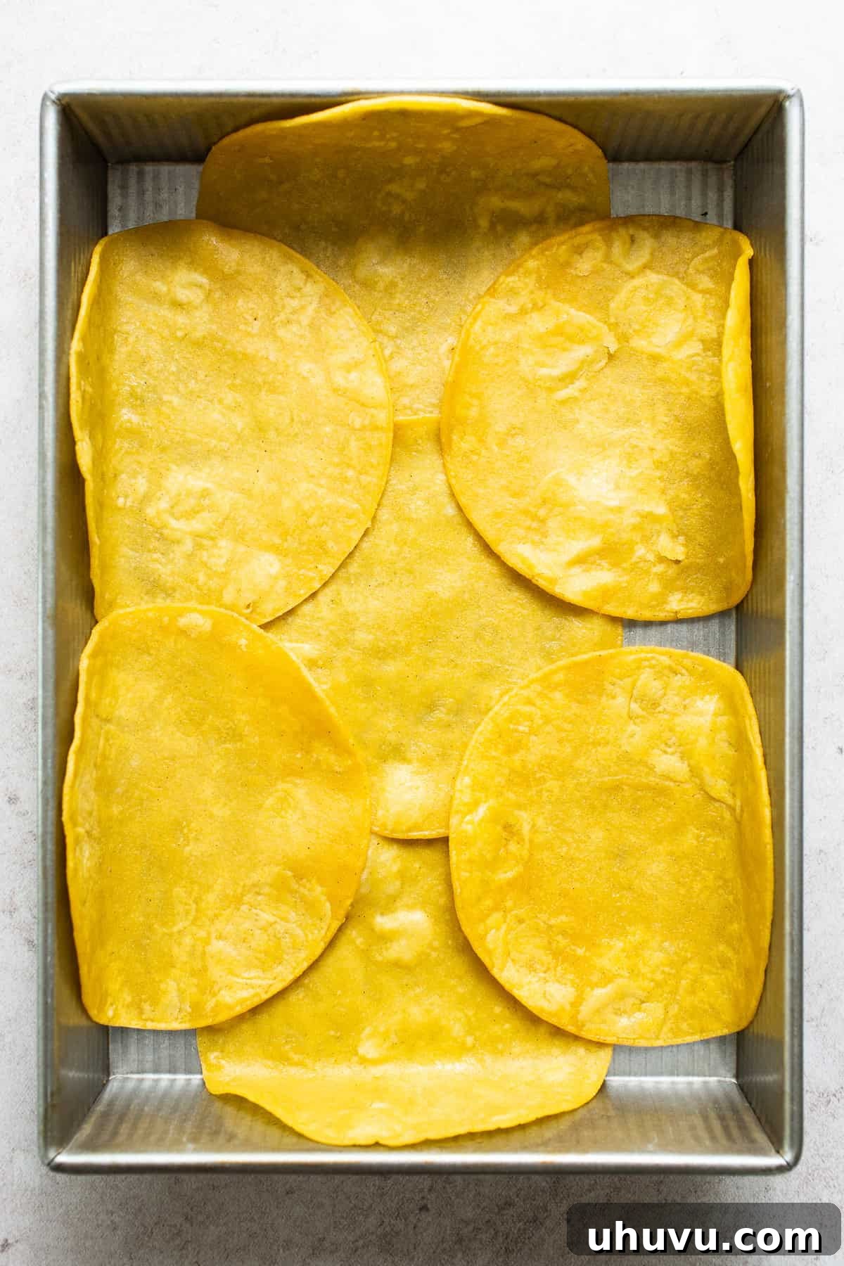 Aztec Tortilla Bake 8 A layer of lightly fried corn tortillas on the bottom of a baking dish.
