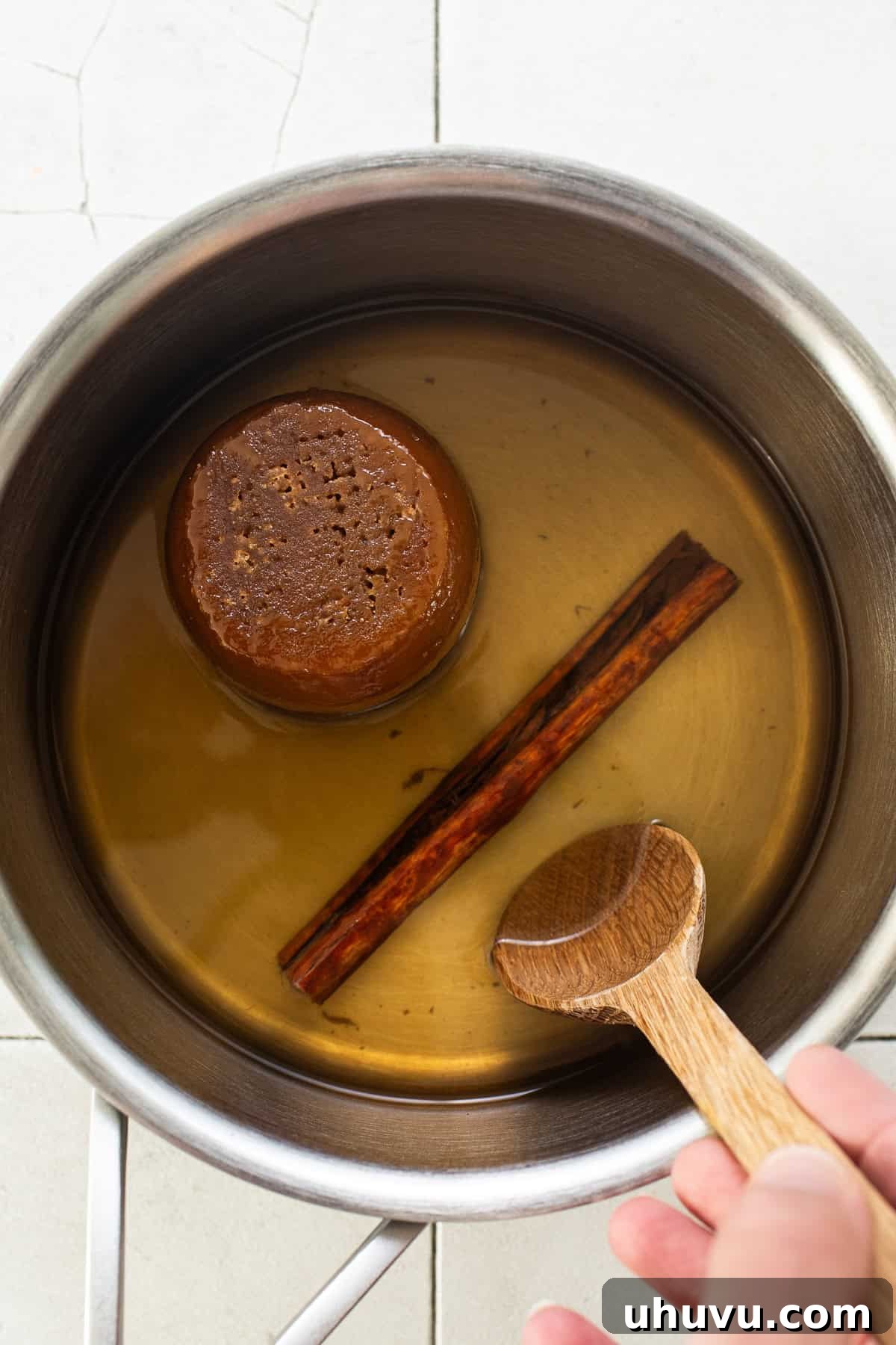 Cozy Walnut Brew 6 A small pot gently simmering with water, a cinnamon stick, and chunks of piloncillo, slowly dissolving and infusing the liquid.