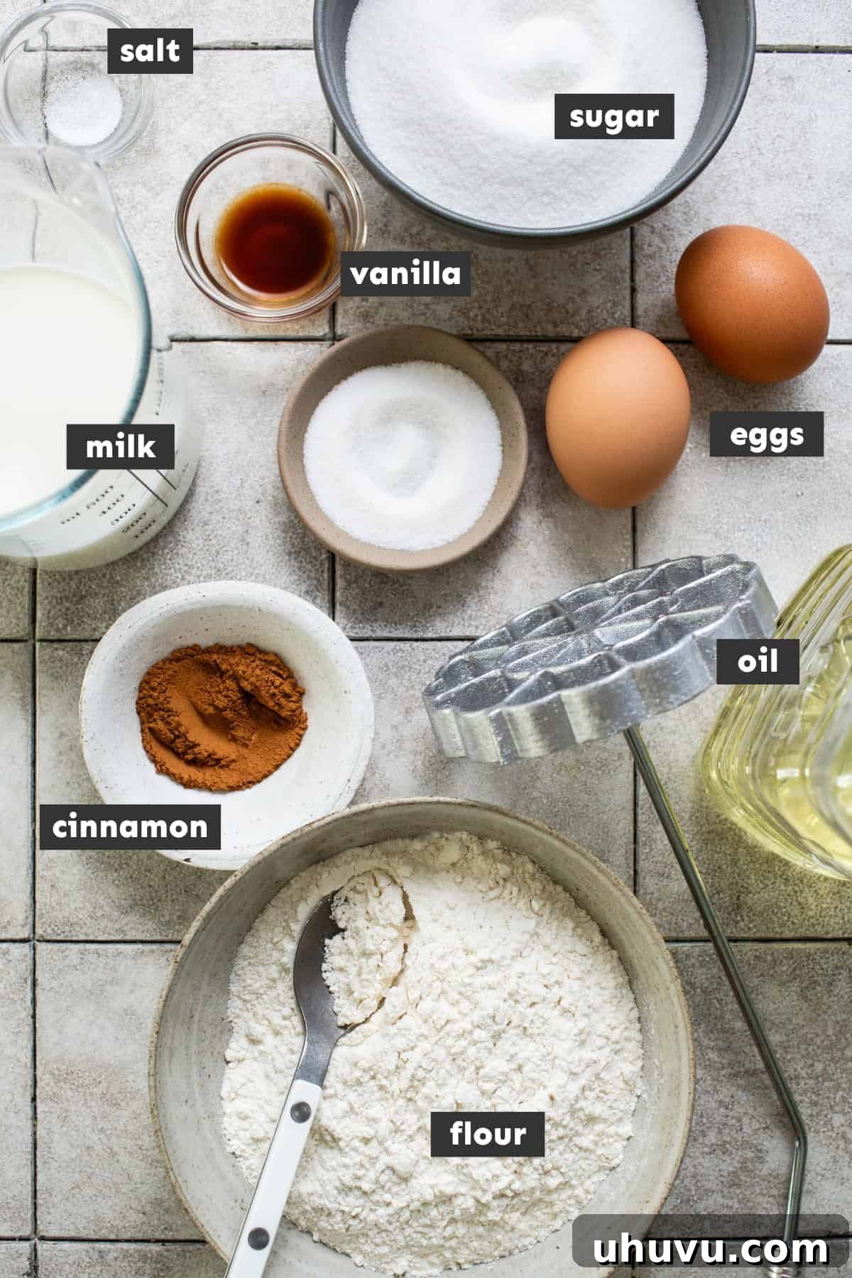 Wind Fritters 4 All of the ingredients for buñuelos de viento are laid out on a table ready to use for this recipe, including flour, sugar, eggs, milk, and vanilla.