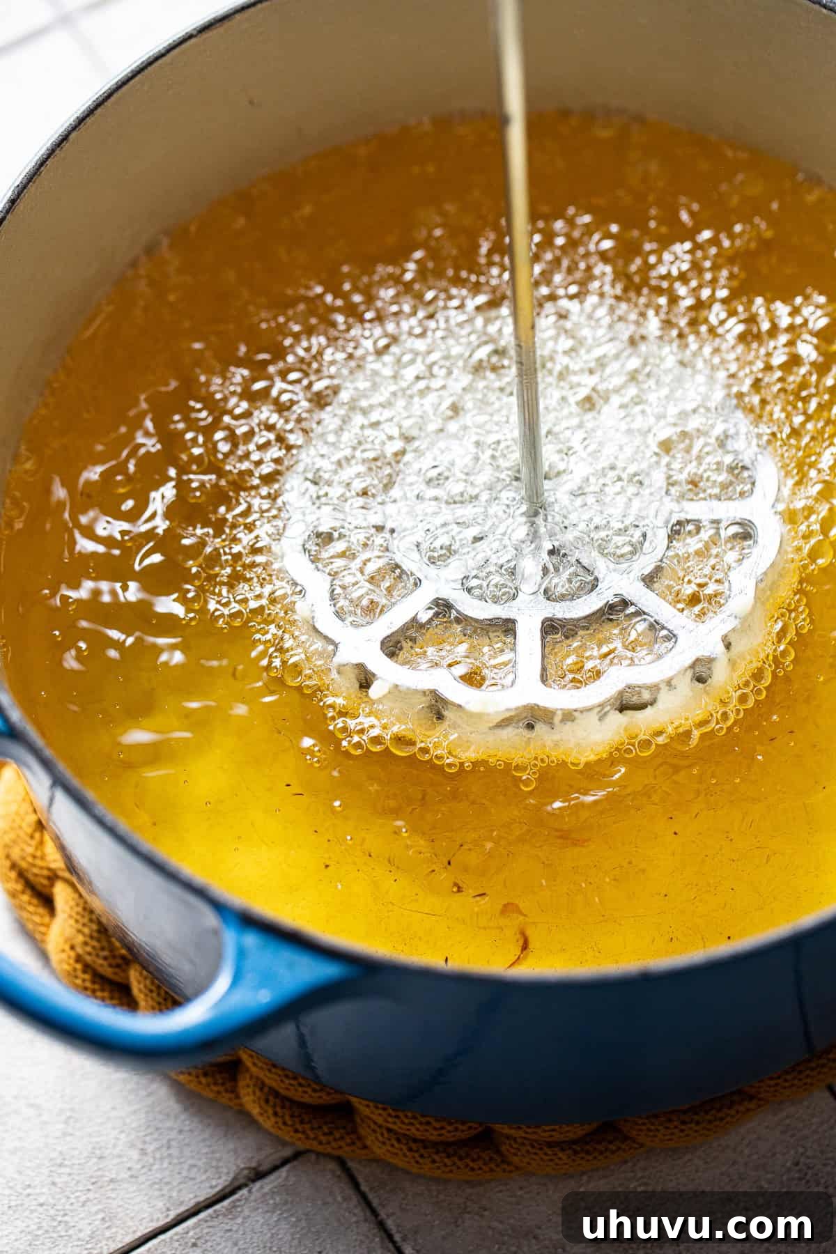 Wind Fritters 8 Delicate buñuelos de viento being fried in hot oil, turning golden brown as they cook.