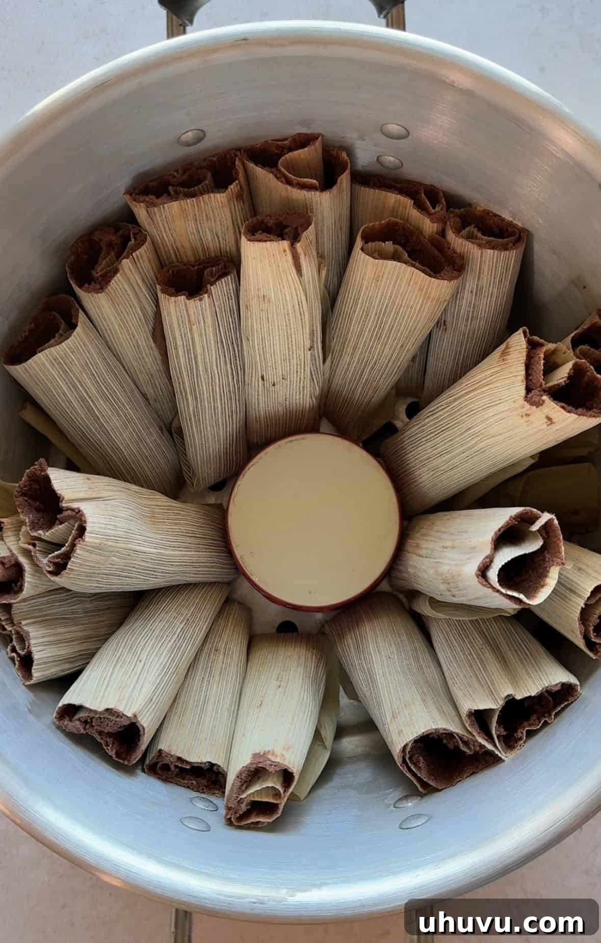 Chocolate tamales arranged neatly in a steamer pot, standing upright and ready to be cooked to perfection.