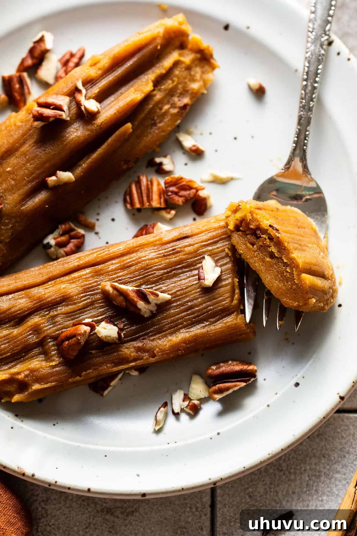 Harvest Pumpkin Tamales 2 A beautifully arranged plate of golden-brown Pumpkin Tamales, garnished with a sprinkle of chopped pecans, ready to be enjoyed as a festive dessert or breakfast.