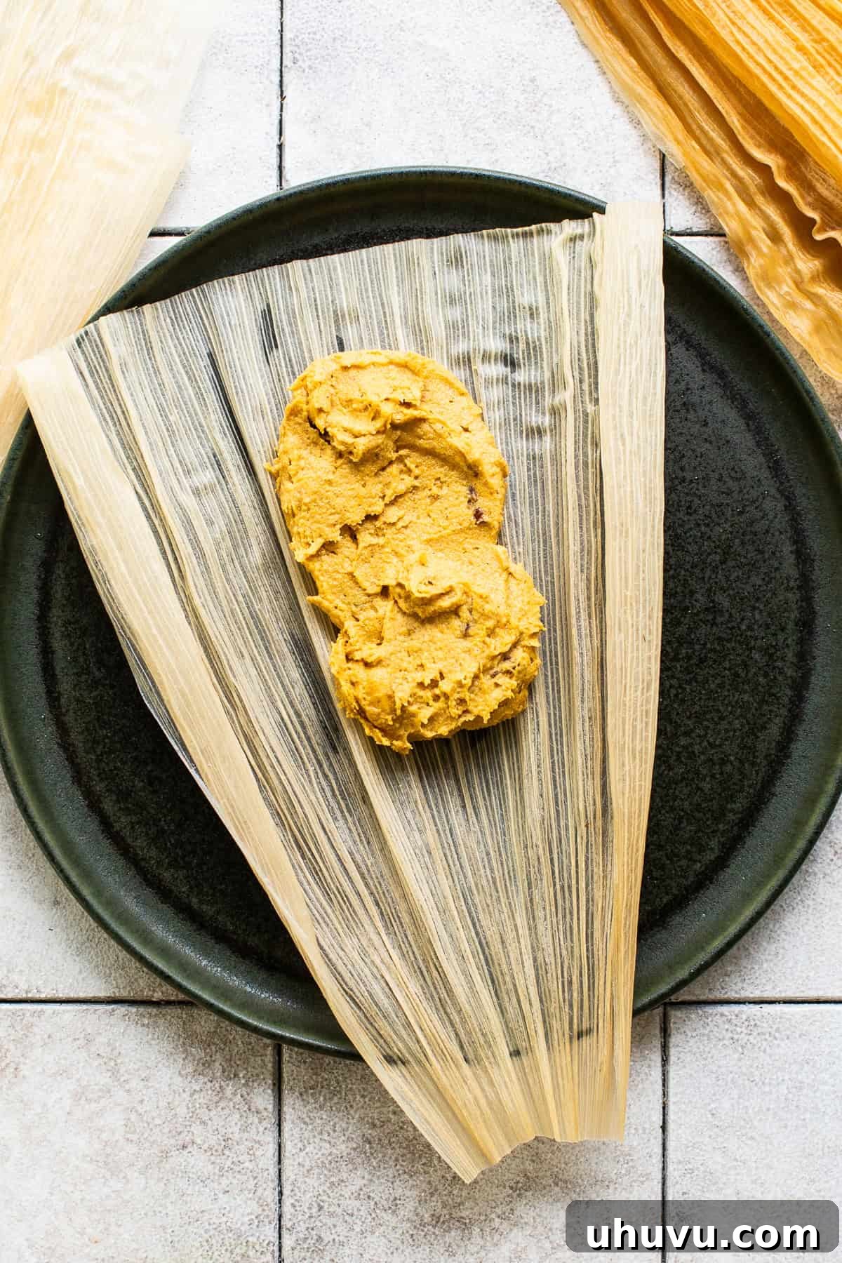 Harvest Pumpkin Tamales 5 A softened corn husk laid open with a scoop of pumpkin tamale masa dough in the center, ready to be folded and assembled into a tamale.