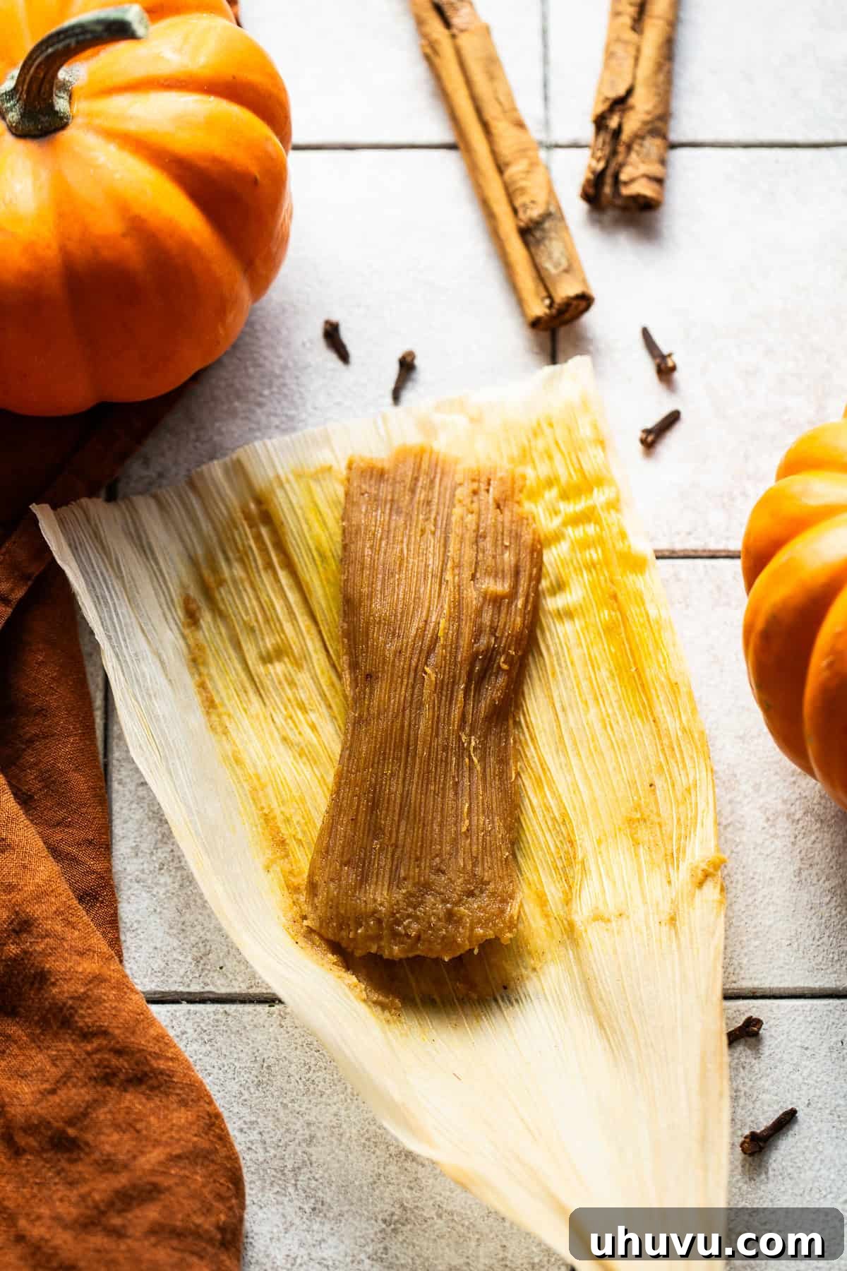 Harvest Pumpkin Tamales 7 A freshly steamed pumpkin tamale, unwrapped from its corn husk and lying gracefully on the husk, showcasing its tender texture.