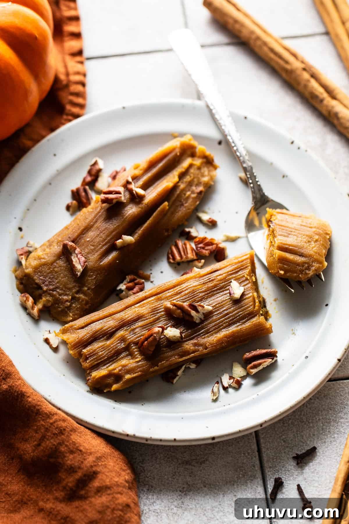 Harvest Pumpkin Tamales 8 A plate of two freshly steamed pumpkin tamales, beautifully garnished with chopped pecans, highlighting their festive and inviting appearance.