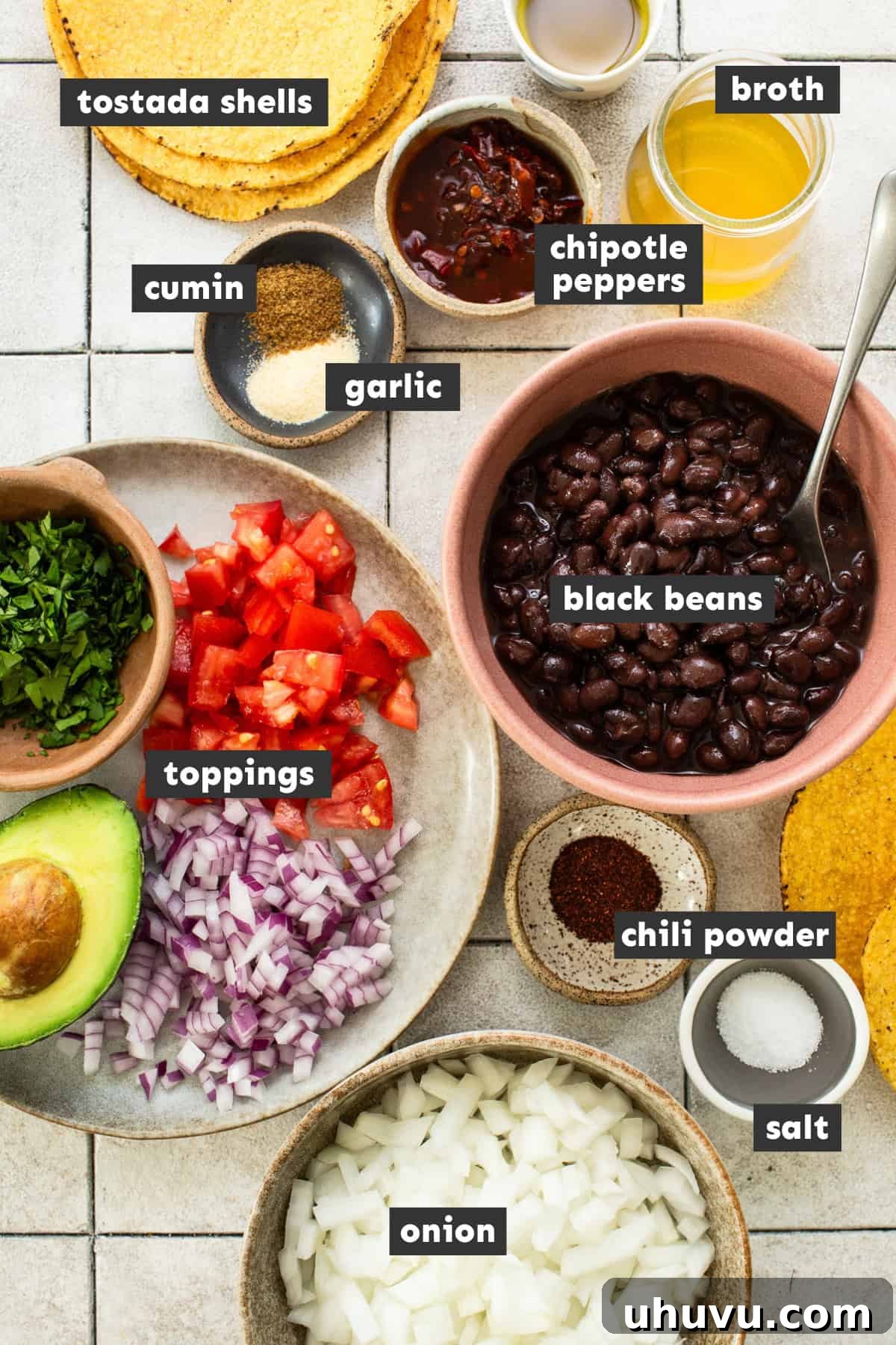 Crispy Black Bean Stacks 3 Freshly prepped ingredients for making black bean tostadas, including a can of black beans, a white onion, chipotle peppers in adobo, and various seasonings, laid out on a kitchen counter.