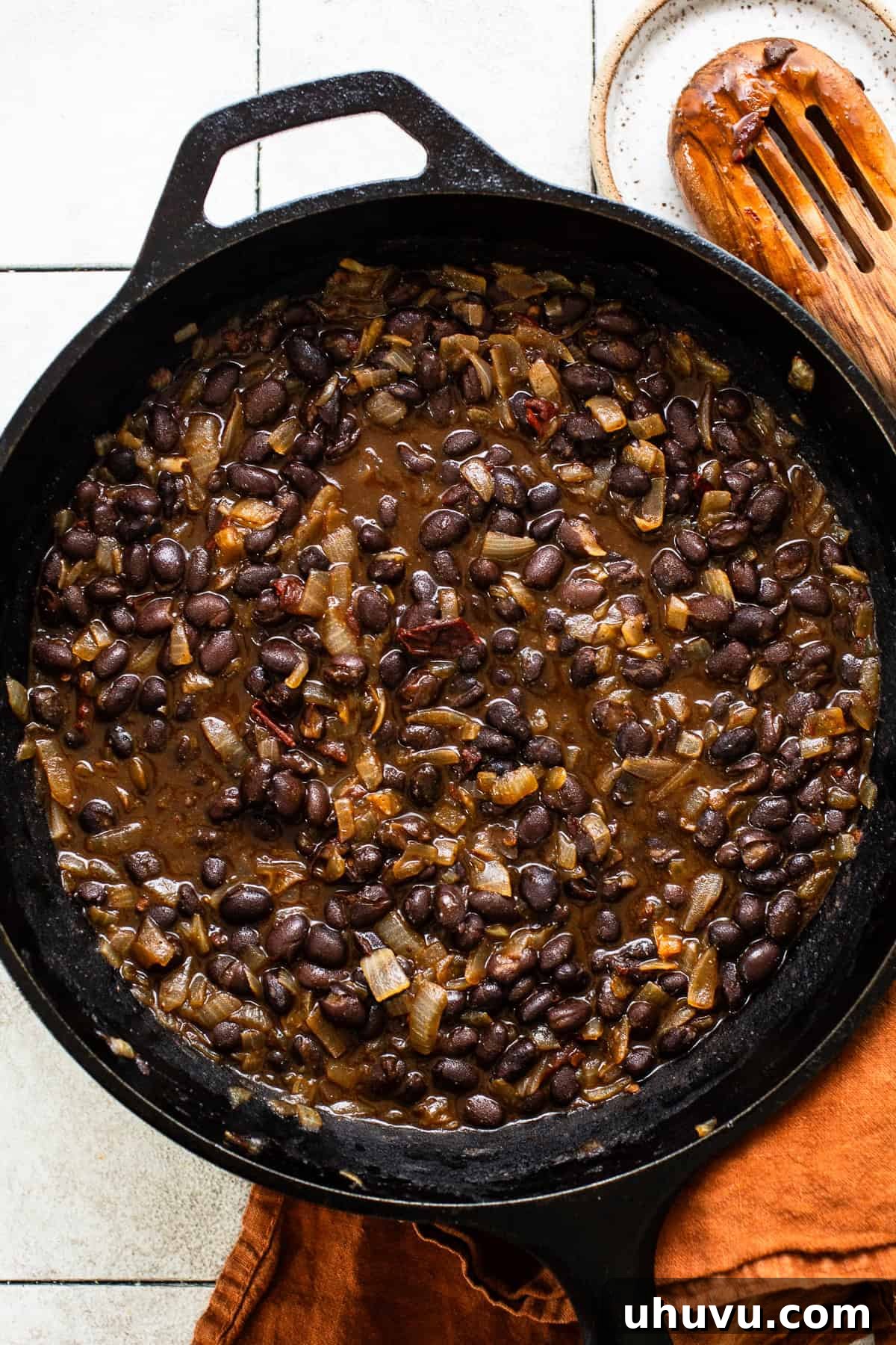 Crispy Black Bean Stacks 5 A simmering mixture of cooked black beans, sautéed onions, and chipotle peppers in adobo sauce in a cast iron skillet, ready to be mashed for black bean tostadas.