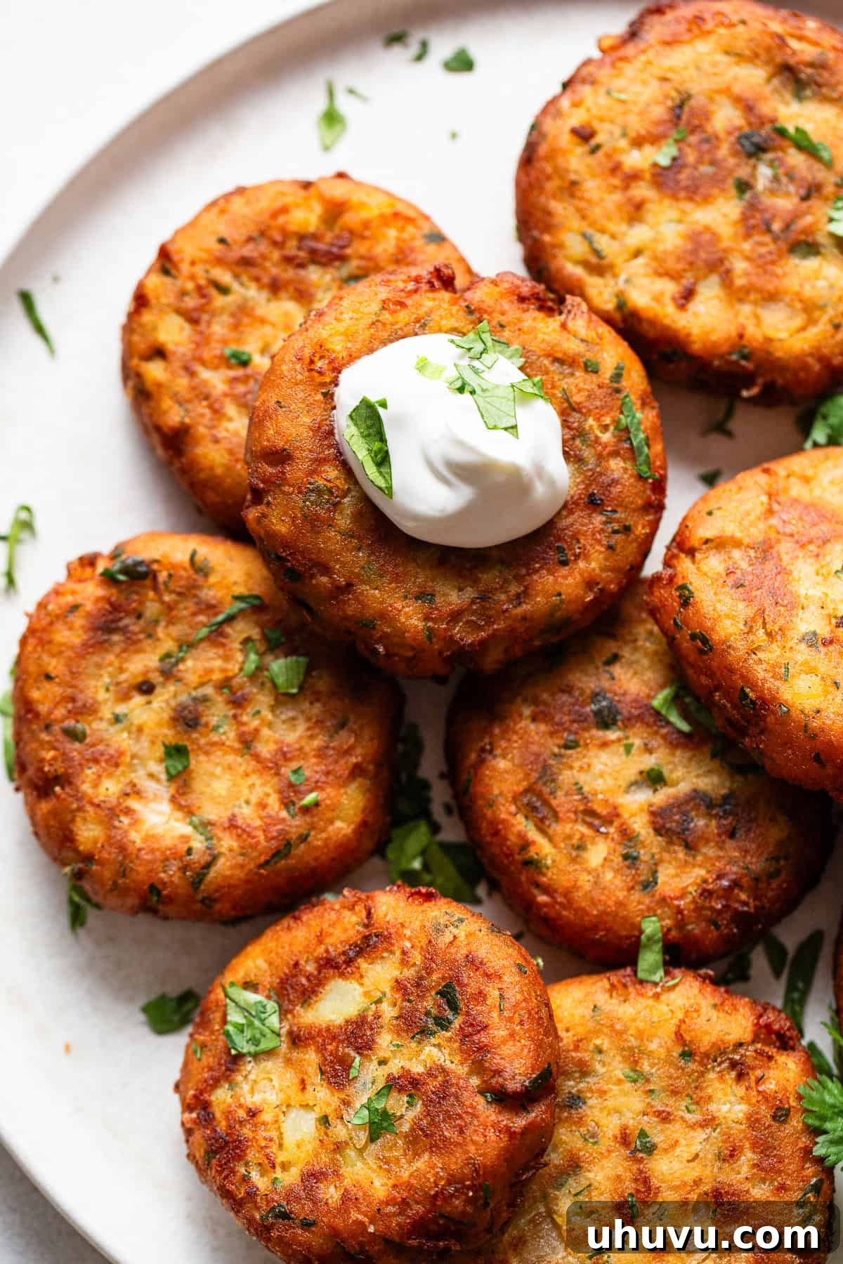 Potato Pancakes 8 Tortitas de papa stacked on a plate served with a dollop of sour cream.