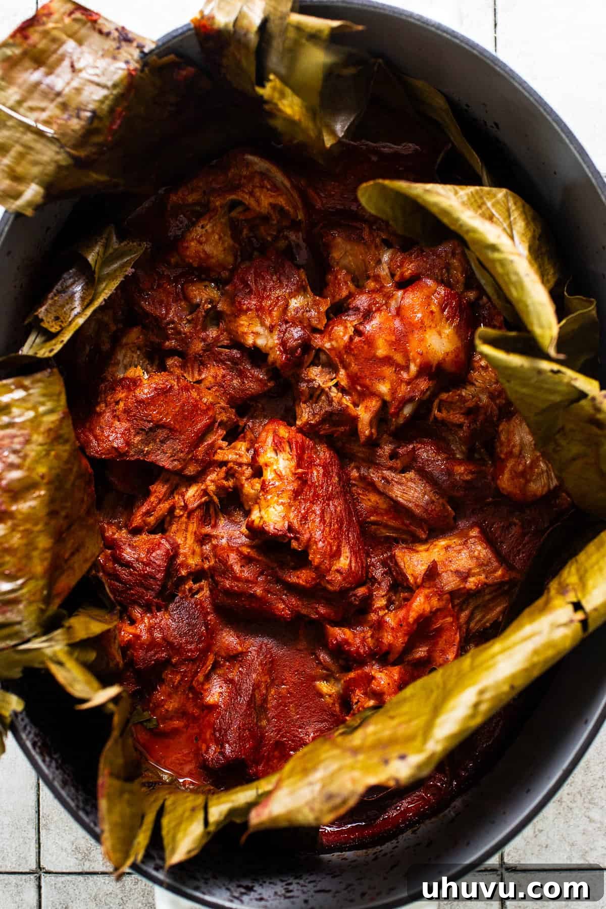 Yucatan's Achiote Slow Roast Pork 2 Traditional Cochinita Pibil slow roasted in a large pot with banana leaves, ready to be shredded and served with fresh garnishes.
