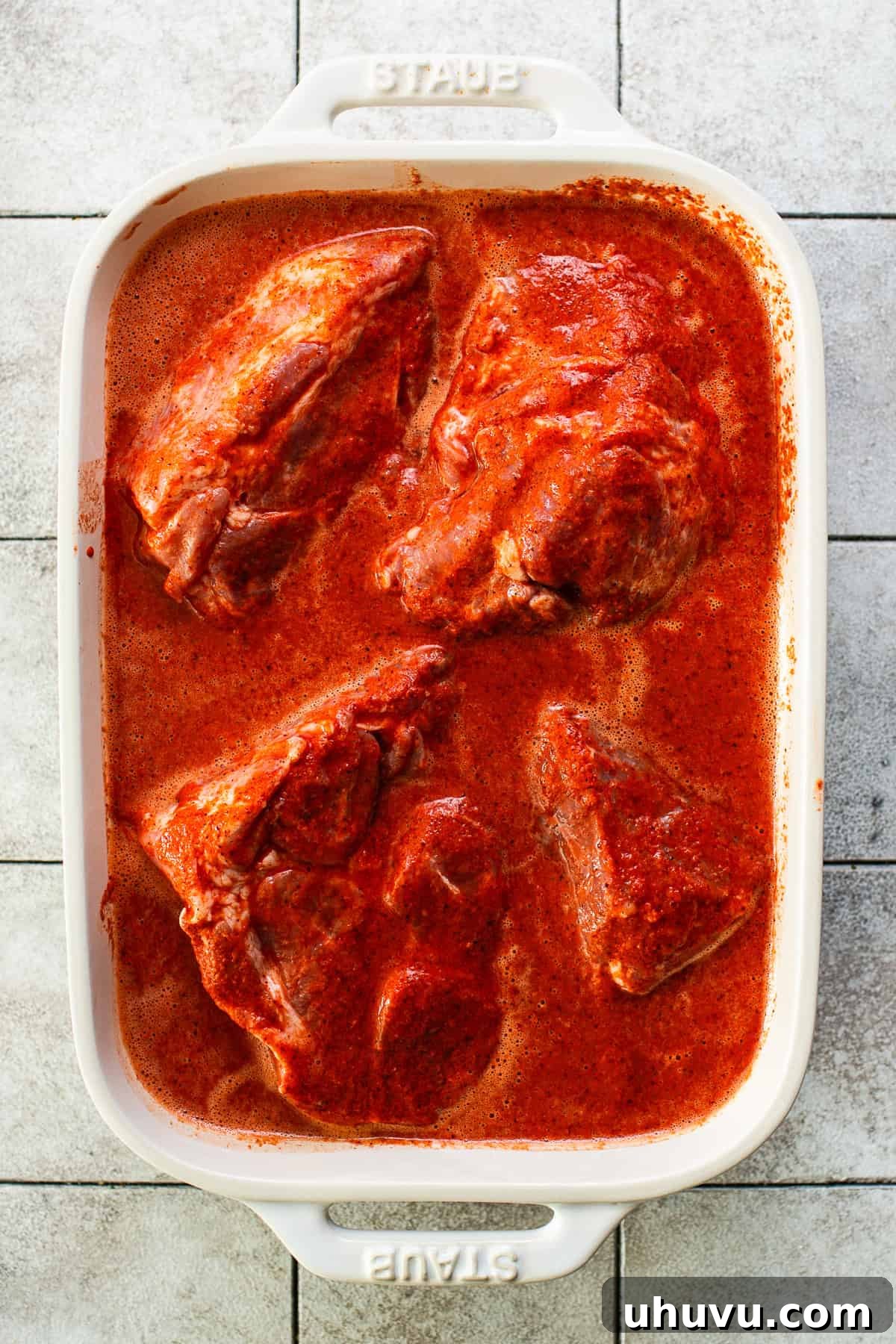 Yucatan's Achiote Slow Roast Pork 5 Large, succulent chunks of pork shoulder thoroughly coated in the rich, reddish-orange cochinita pibil marinade in a mixing bowl.