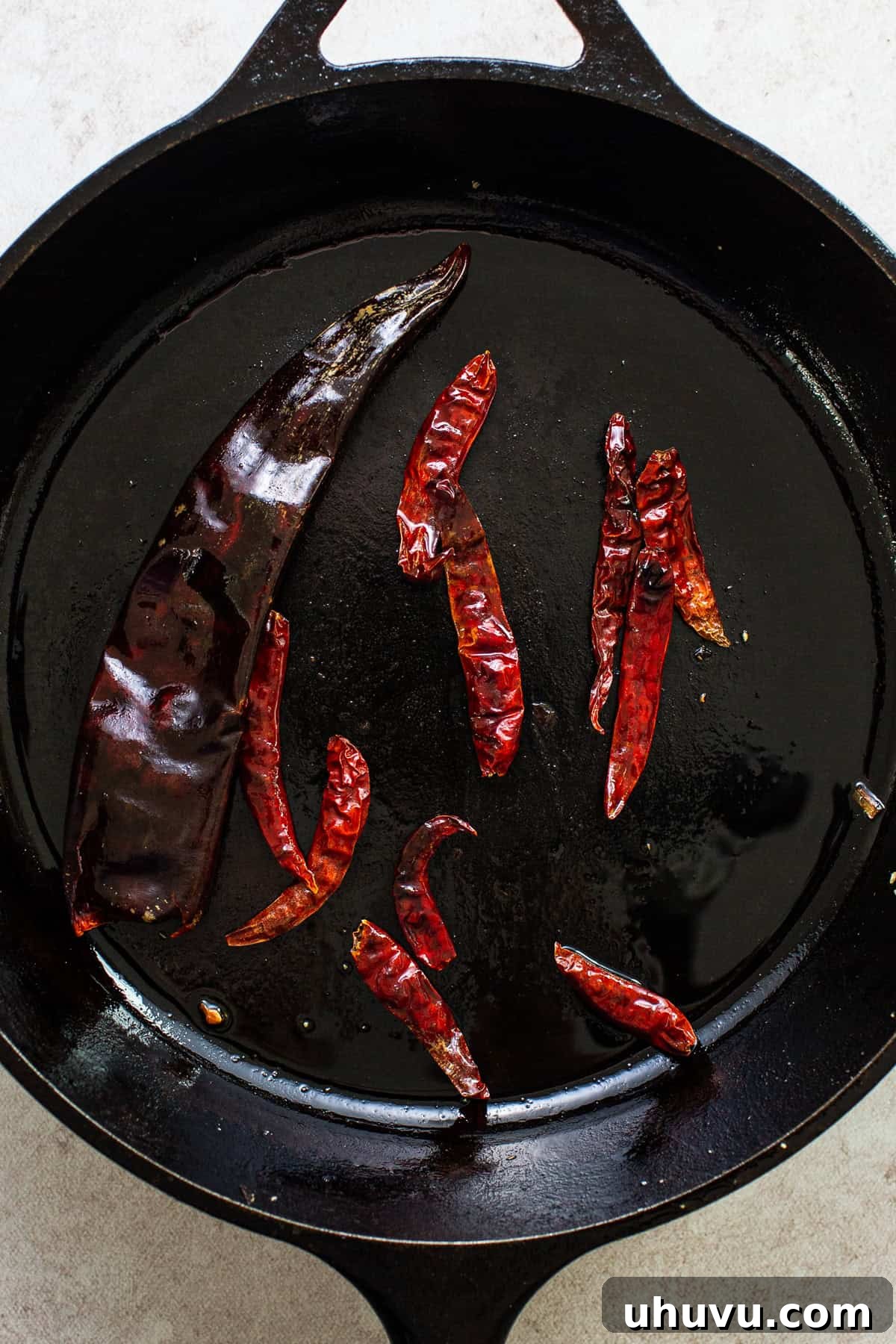 Creamy Peanut Salsa 5 Árbol and guajillo chiles being dry-toasted in the same skillet, puffing up and developing brown marks.