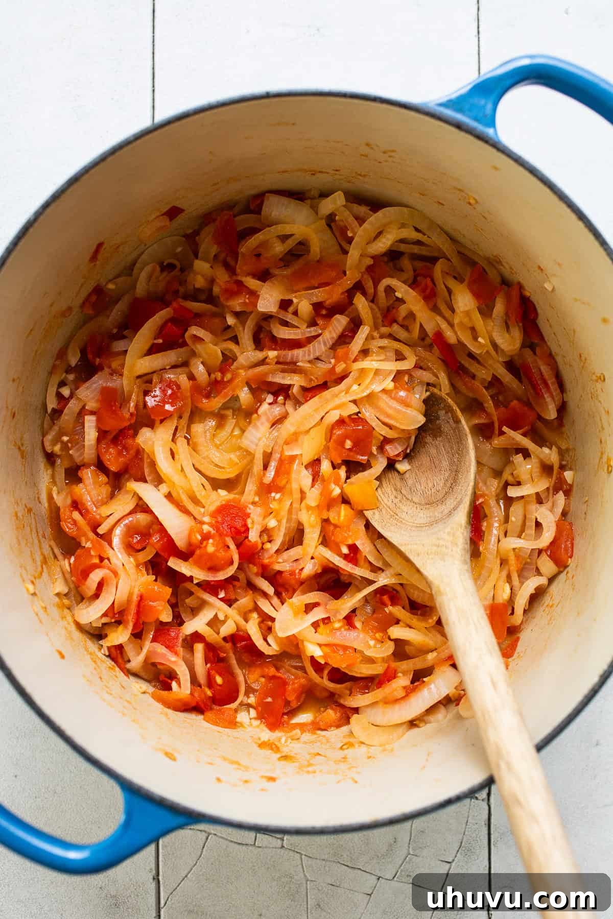 Creamy Cheese Soup 5 Finely sliced onions, chopped Roma tomatoes, and minced garlic being sautéed in a large pot or Dutch oven.