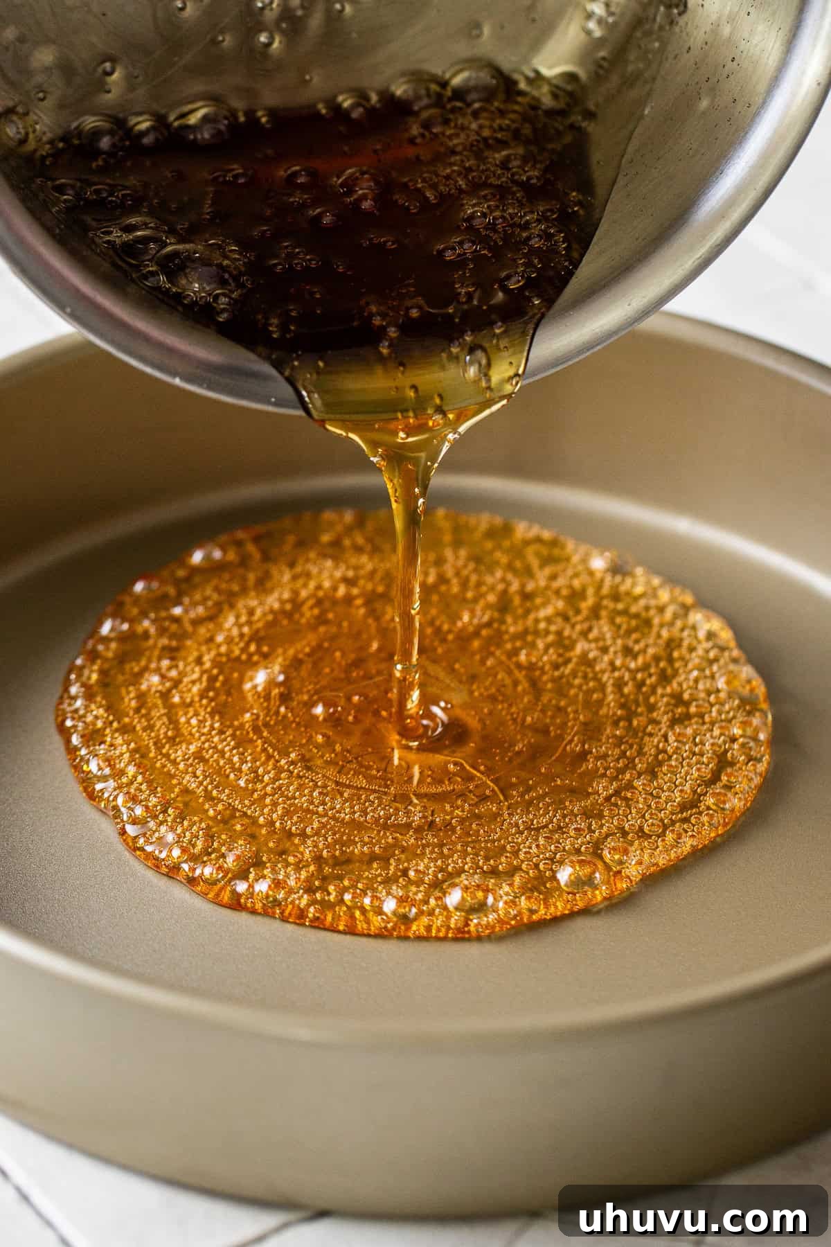 Decadent Chocolate Flan 4 Glistening golden caramel being carefully poured and swirled into the bottom of a round cake pan, preparing the base for the flan.