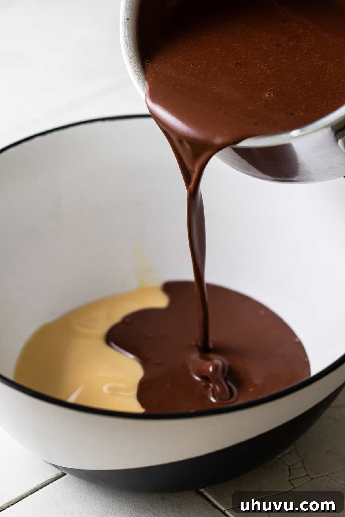 Decadent Chocolate Flan 5 A rich, melted chocolate mixture being poured into a bowl containing sweetened condensed milk, ready to be combined into the flan base.
