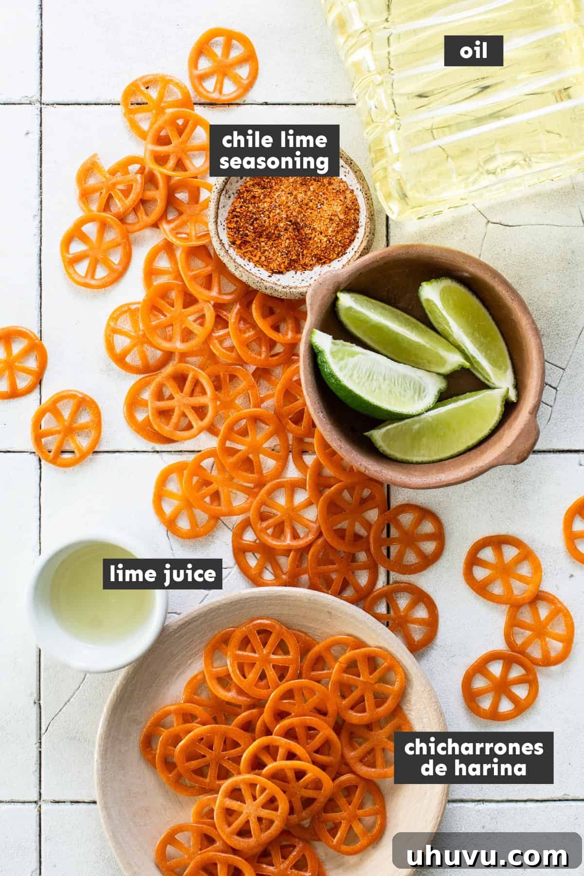A collection of ingredients laid out on a table, including dry chicharrones de harina, a bottle of oil, and fresh limes, ready for preparation.