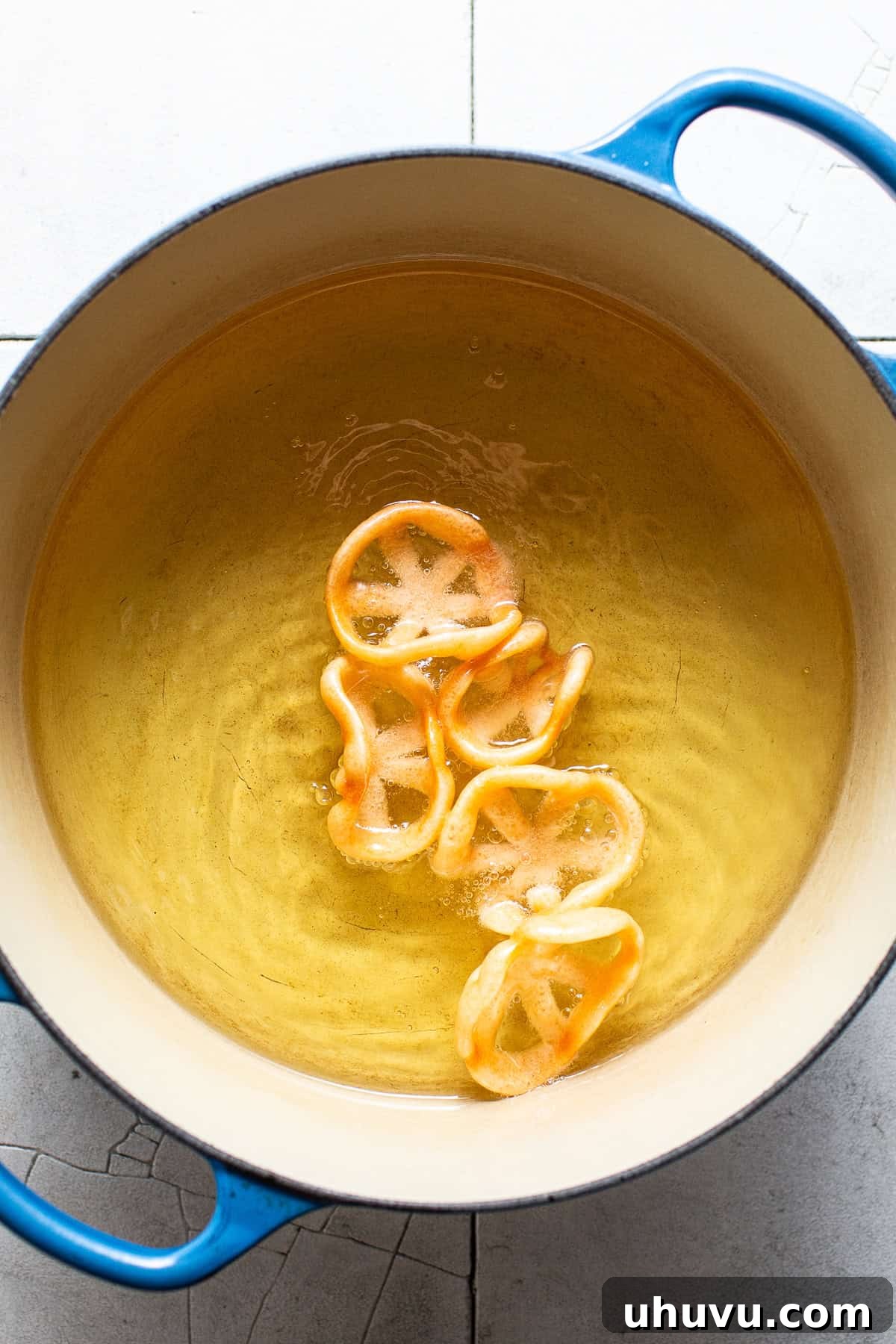 Chicharrones de harina (duros) frying in hot oil, actively puffing up.