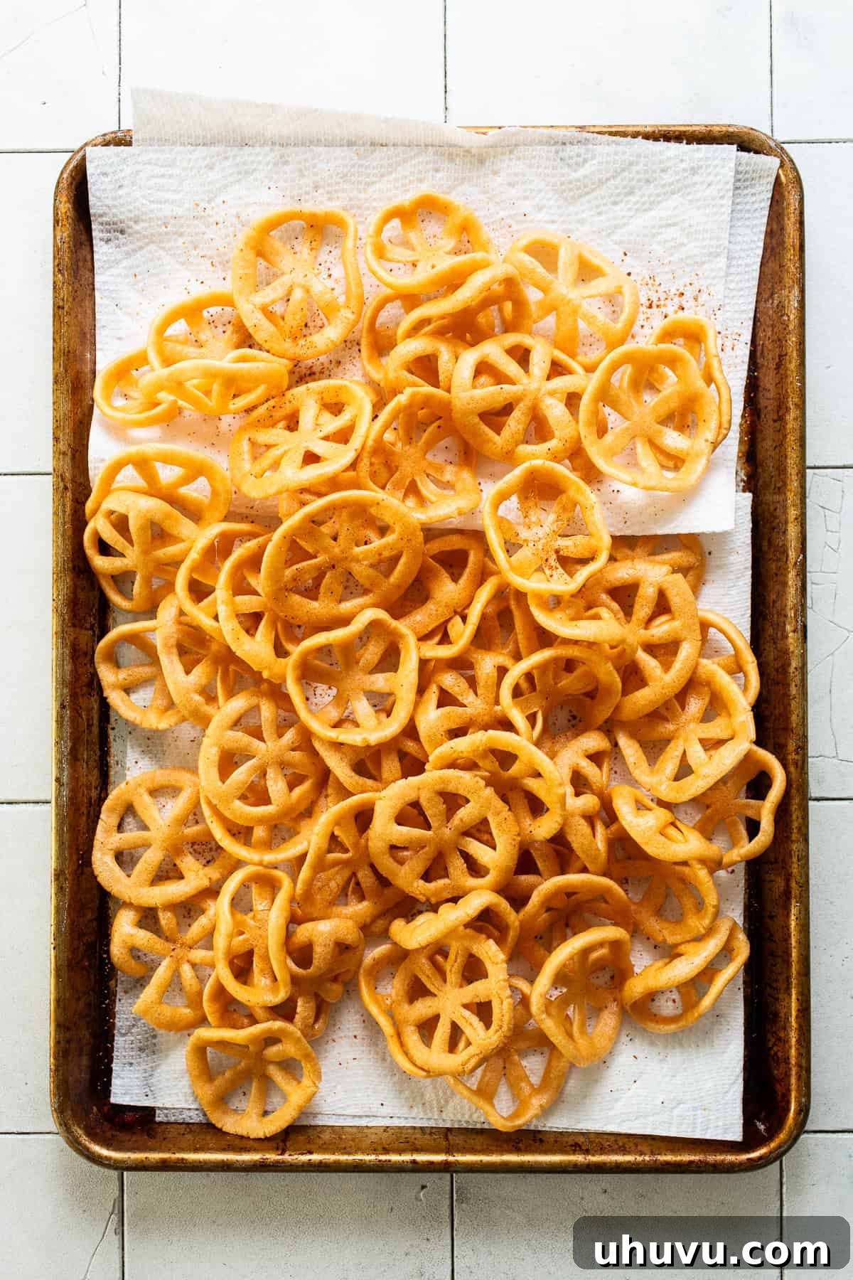 Chicharrones de harina arranged on a sheet pan lined with paper towels to absorb oil.