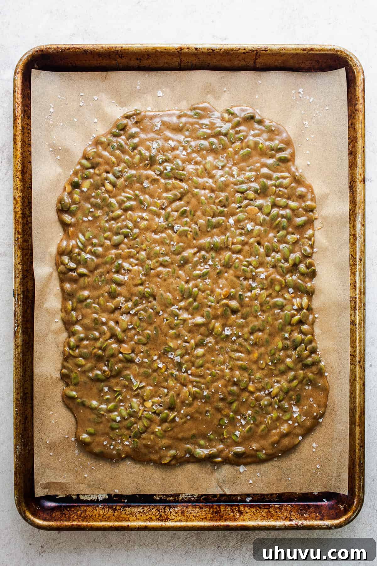 Crispy Pumpkin Seed Brittle 6 The hot, liquid brittle candy mixture freshly poured and expertly spread out into a thin, even layer on a prepared baking sheet, ready for cooling.