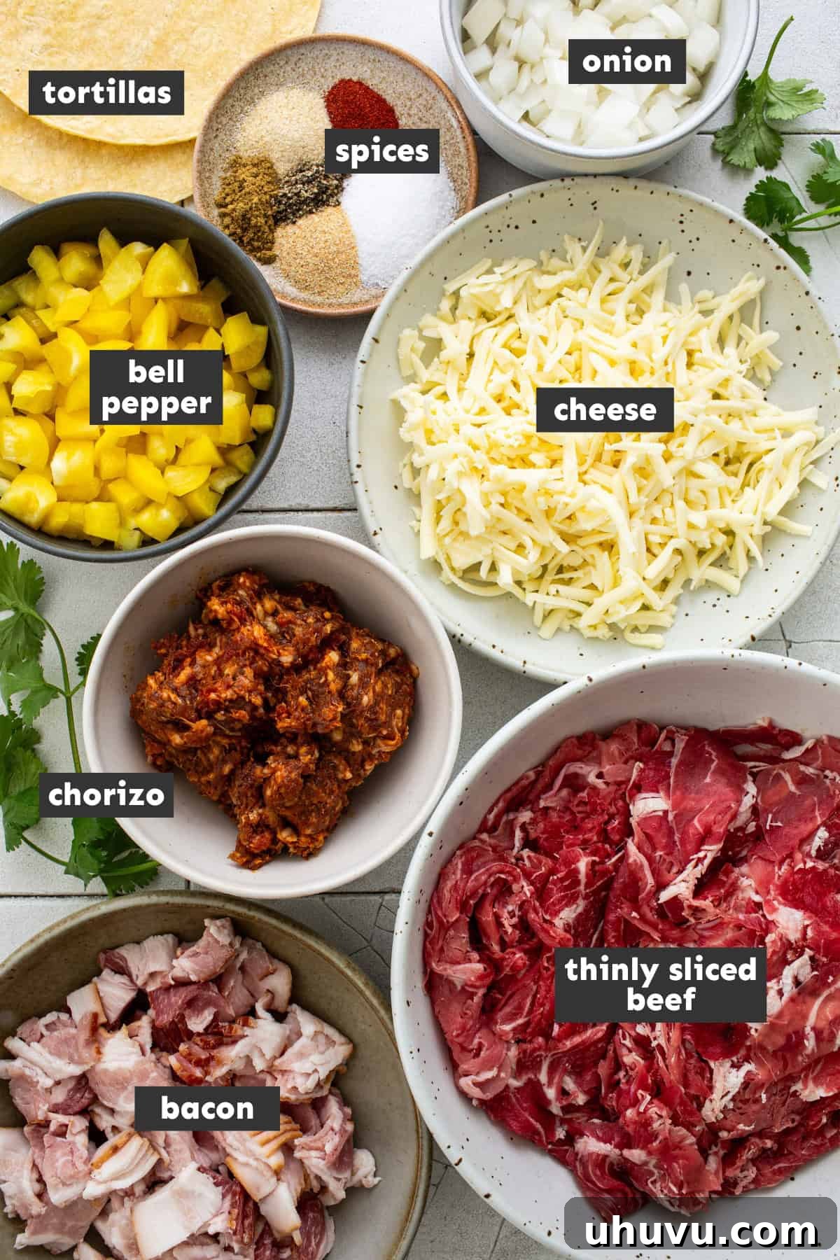 A spread of fresh ingredients on a wooden table, including thinly sliced steak, diced bacon, chorizo, bell peppers, onions, and various seasonings, ready for making Tacos de Alambre.