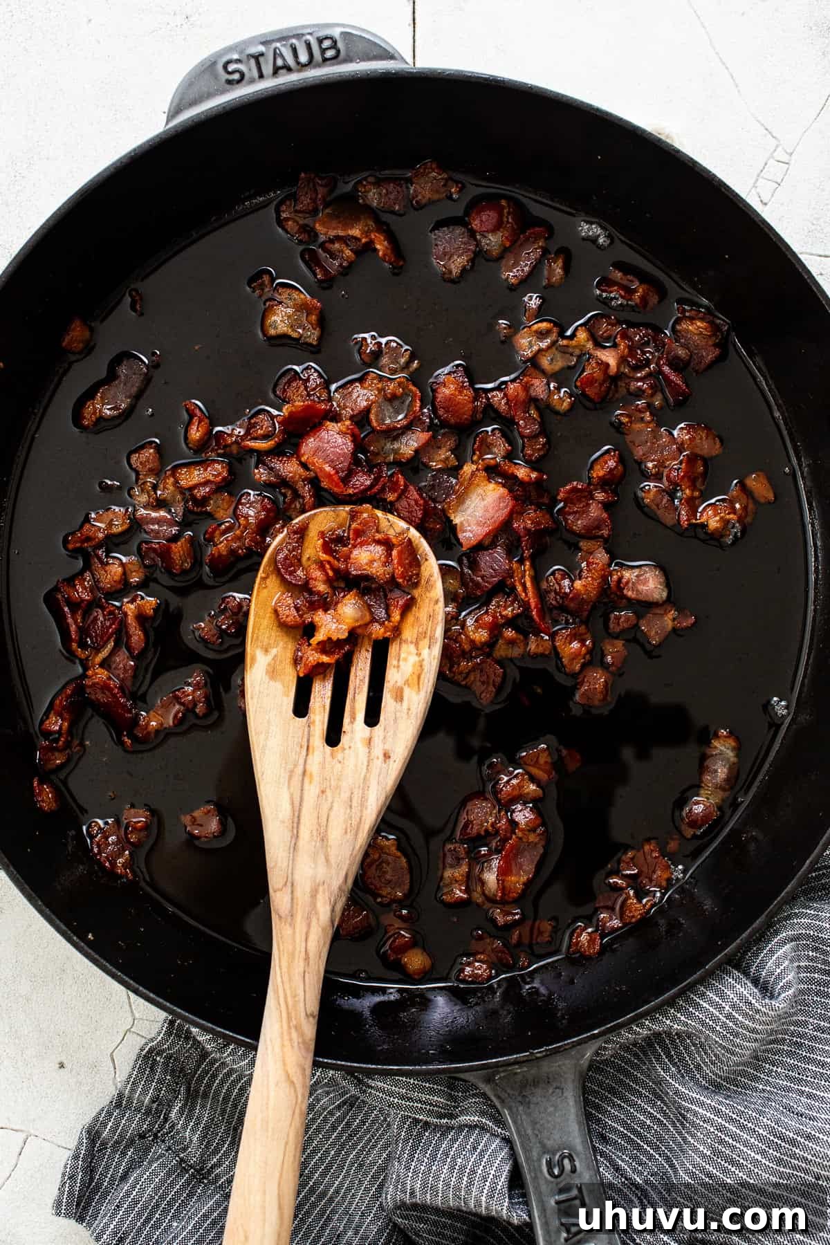 Diced thick-cut bacon sizzling and crisping in a hot skillet, rendering its flavorful fat.