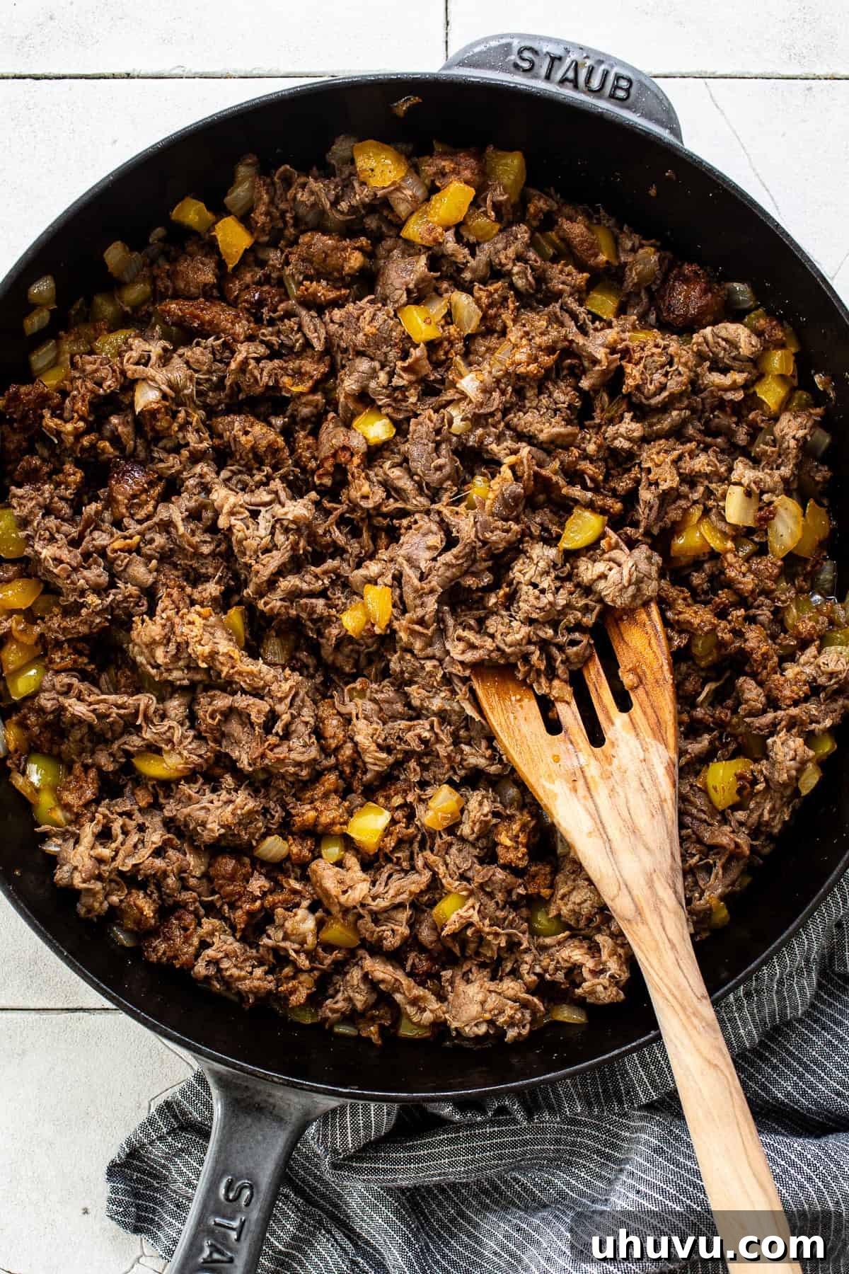 A vibrant mix of shaved steak, chorizo, bell peppers, and onions sautéing in a skillet, creating a delicious stir-fry for Tacos de Alambre.