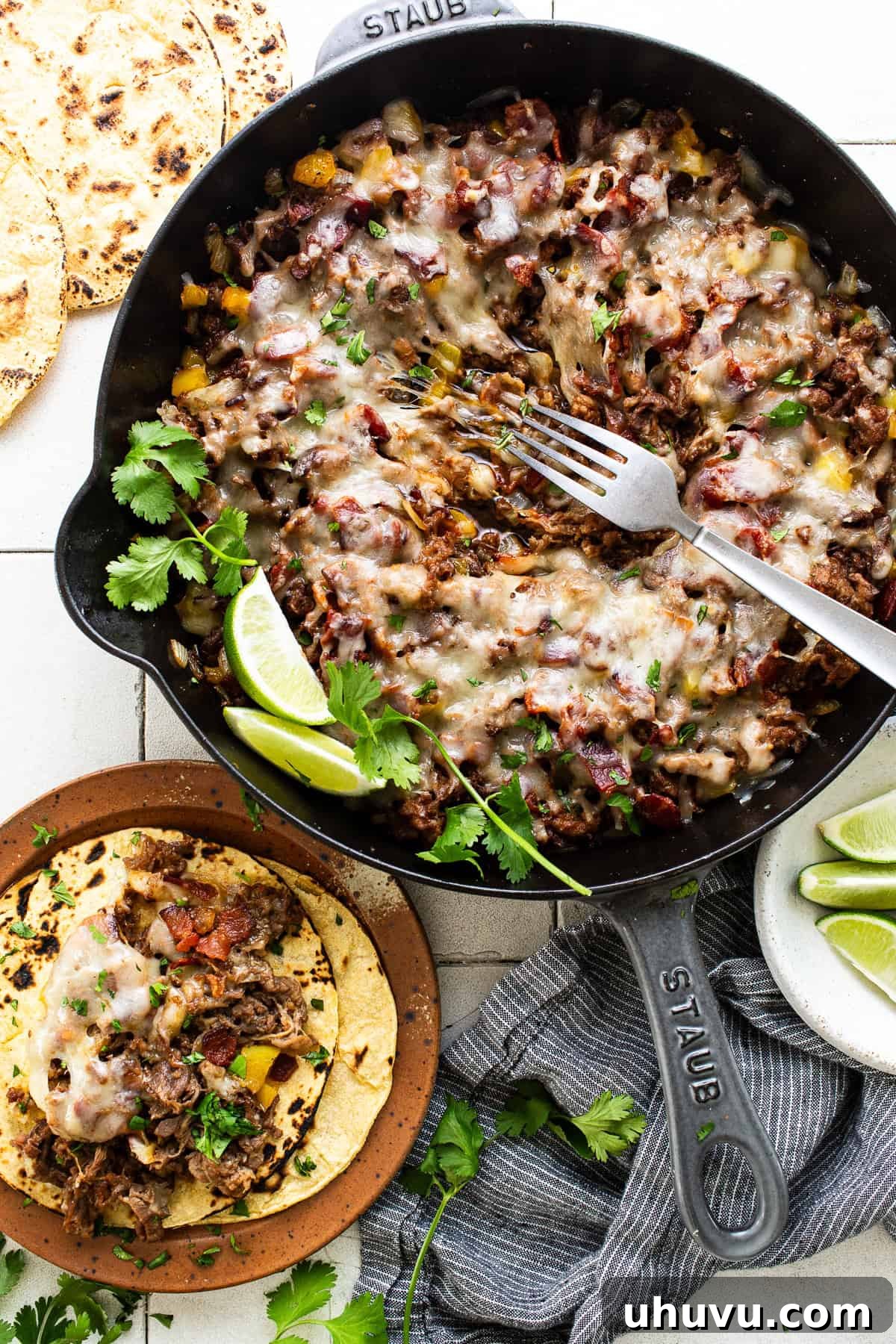 The finished Tacos de Alambre mixture in a skillet, topped with a generous layer of perfectly melted, bubbly cheese and sprinkled with fresh cilantro.